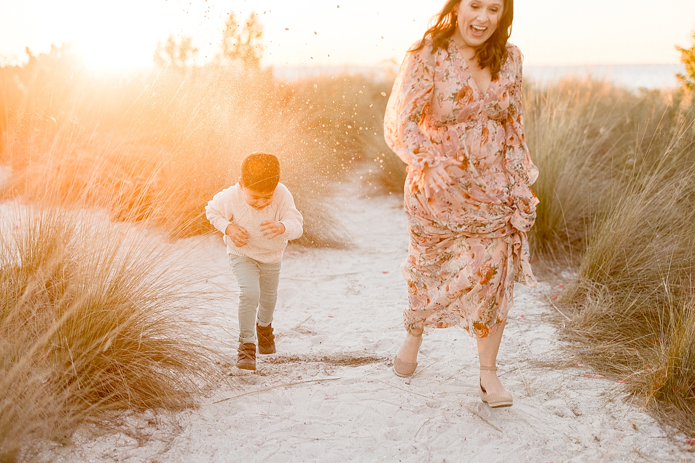 Mom and son running through the sand with the sun setting behind them. Photos by Brittany Elise Photography.
