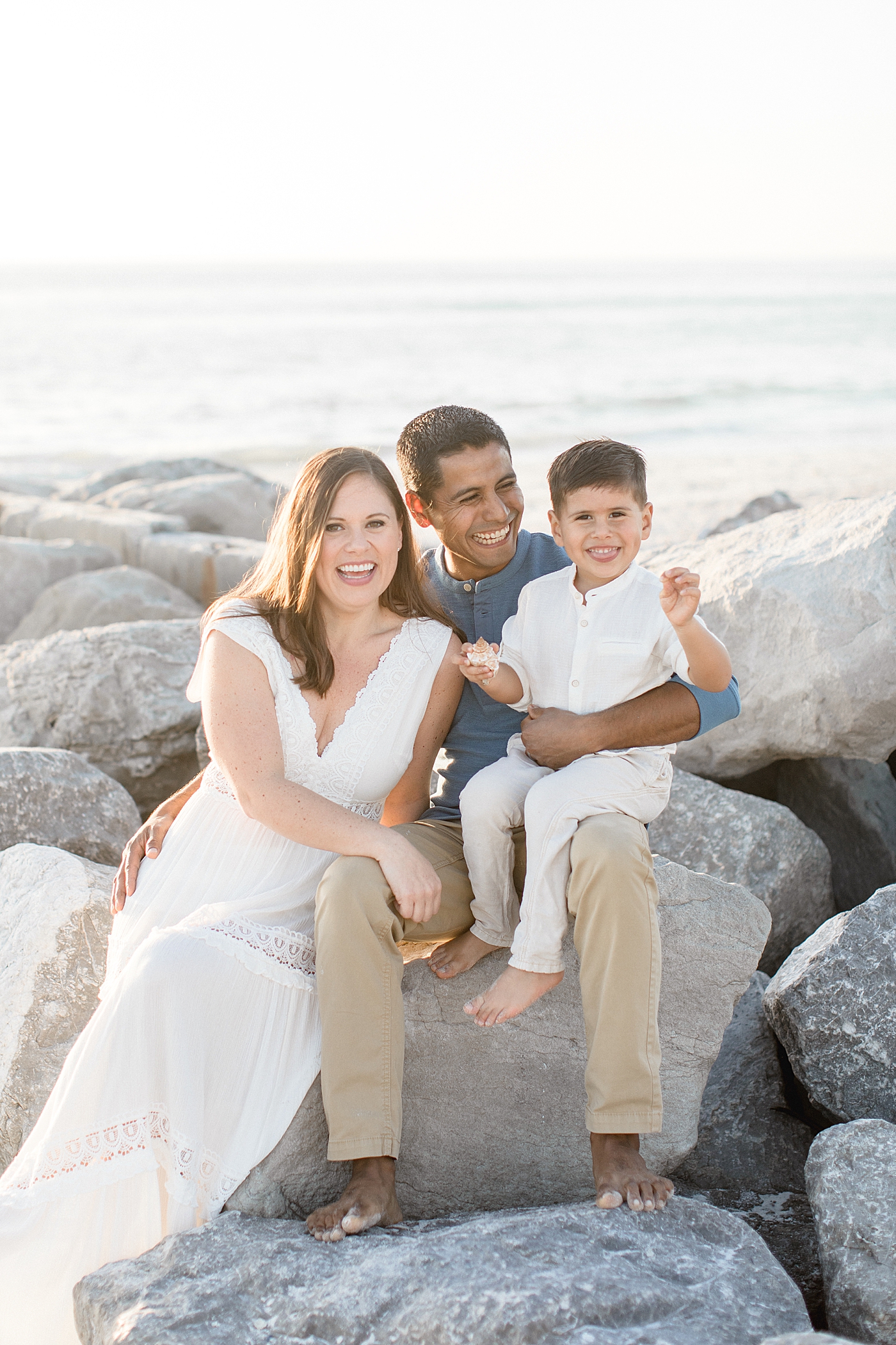 Family sitting on rocks on the beach in Tampa | Brittany Elise Photography