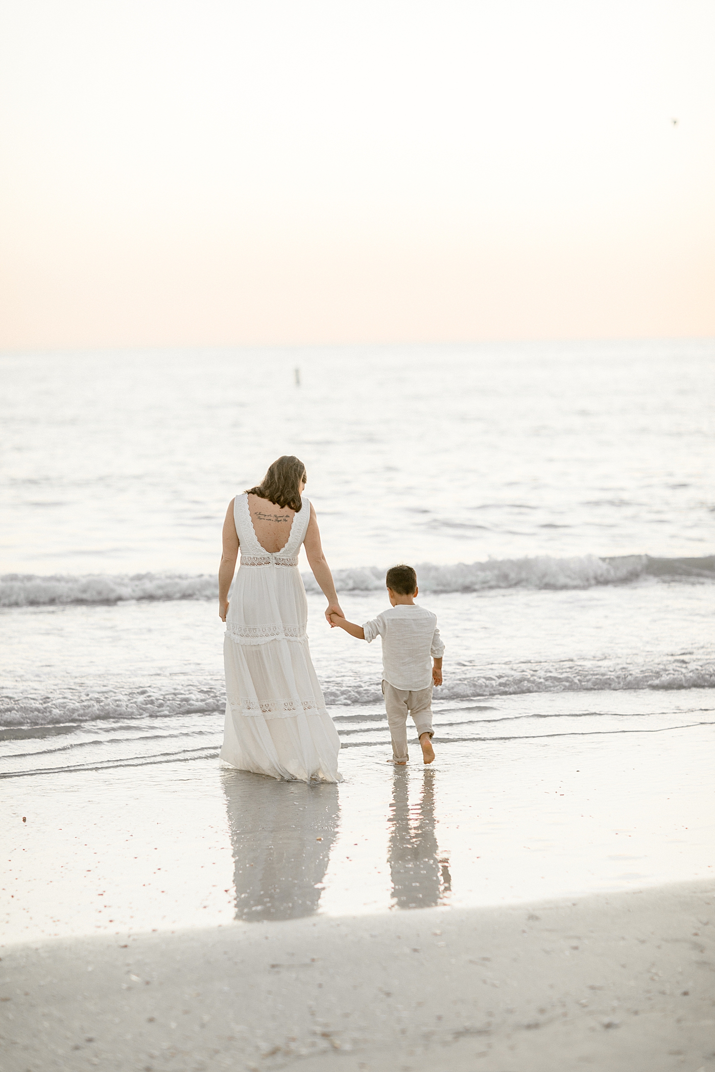 Mom and son holding hands by the water on the beach at sunset. Photos by Brittany Elise Photography.
