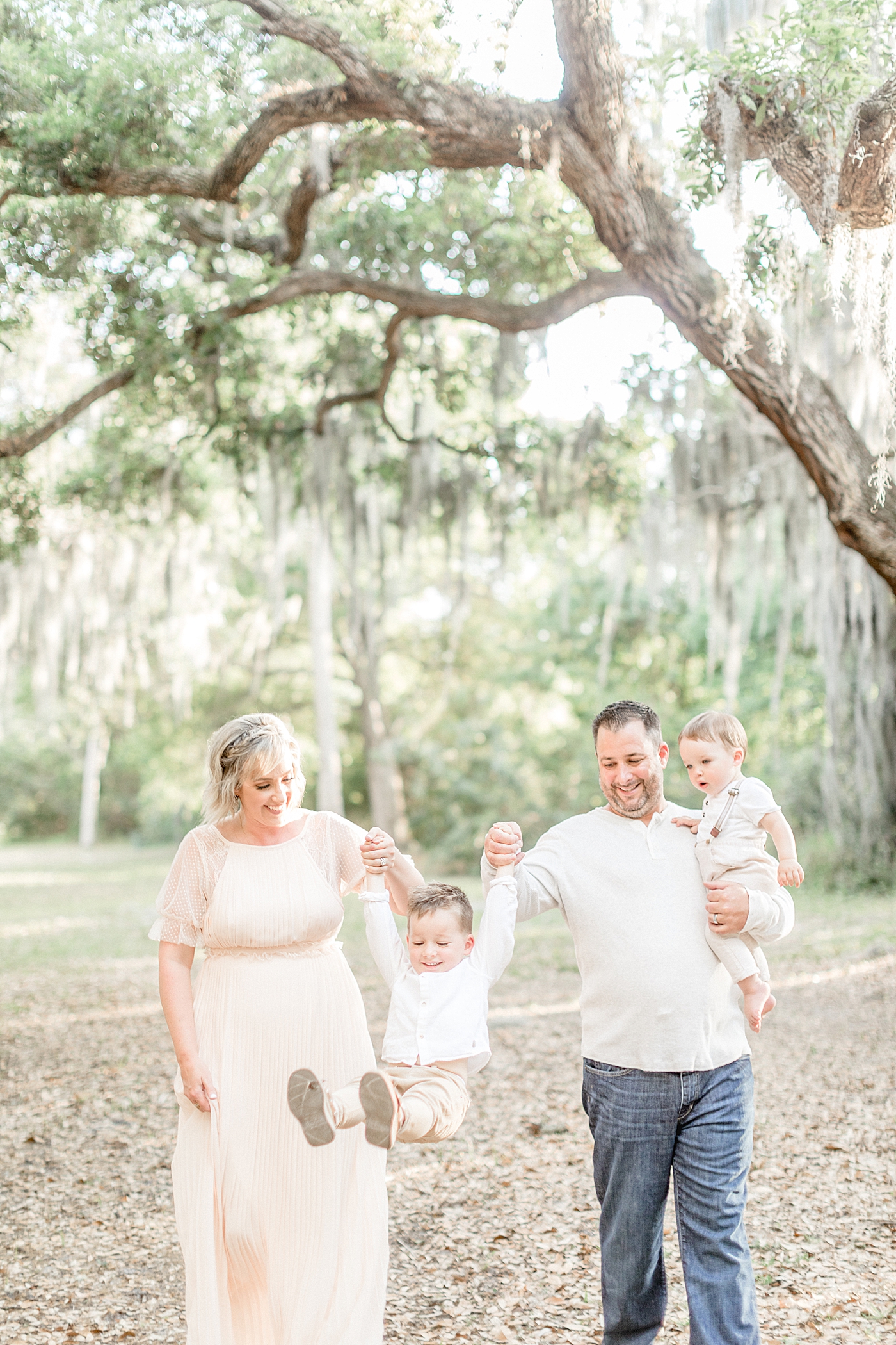 Mom and Dad swinging older son and holding one year old for family photos. Photo by Brittany Elise Photography.
