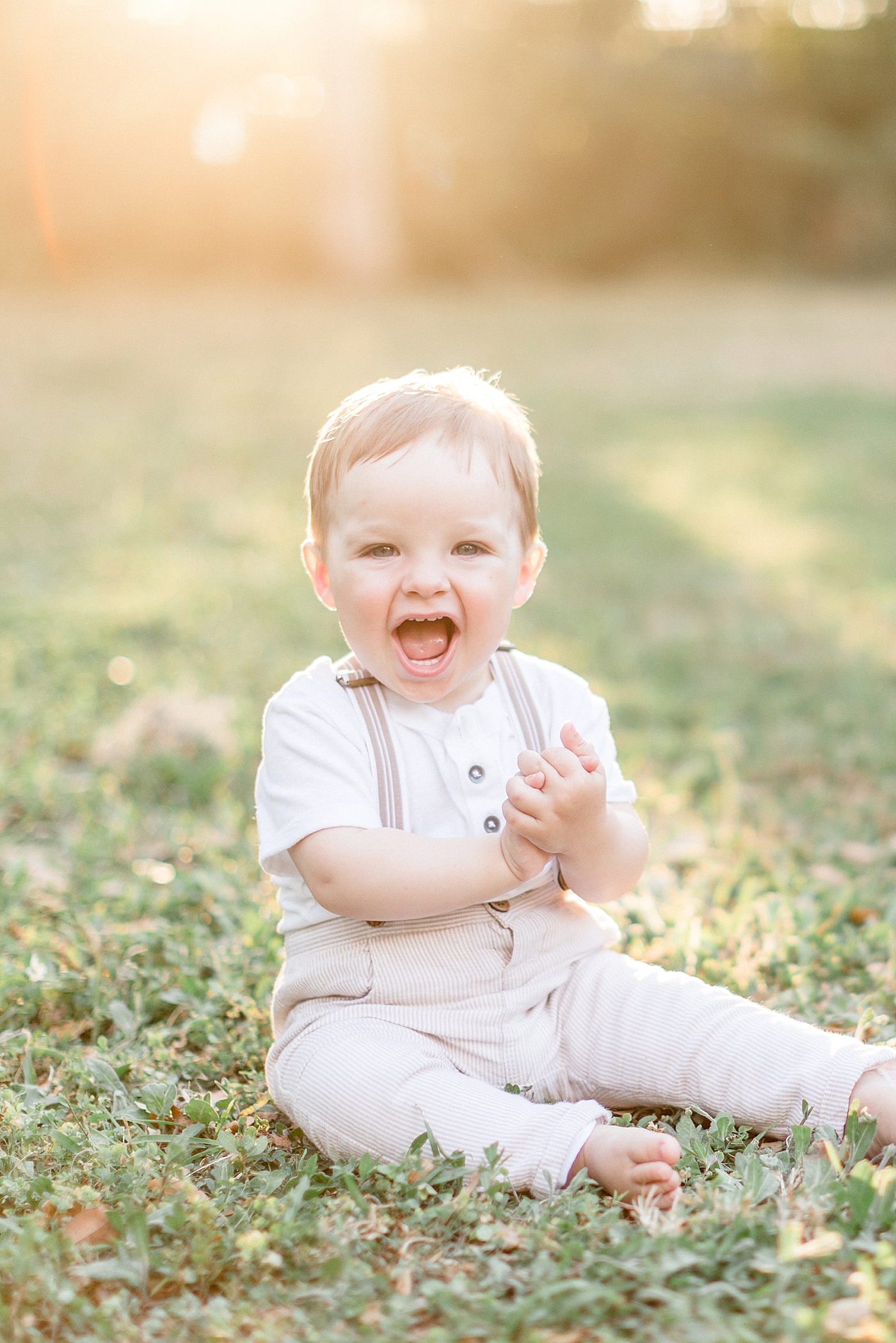 One year old boy sitting in field at sunset for his first birthday photoshoot. Photo by Brittany Elise Photography.