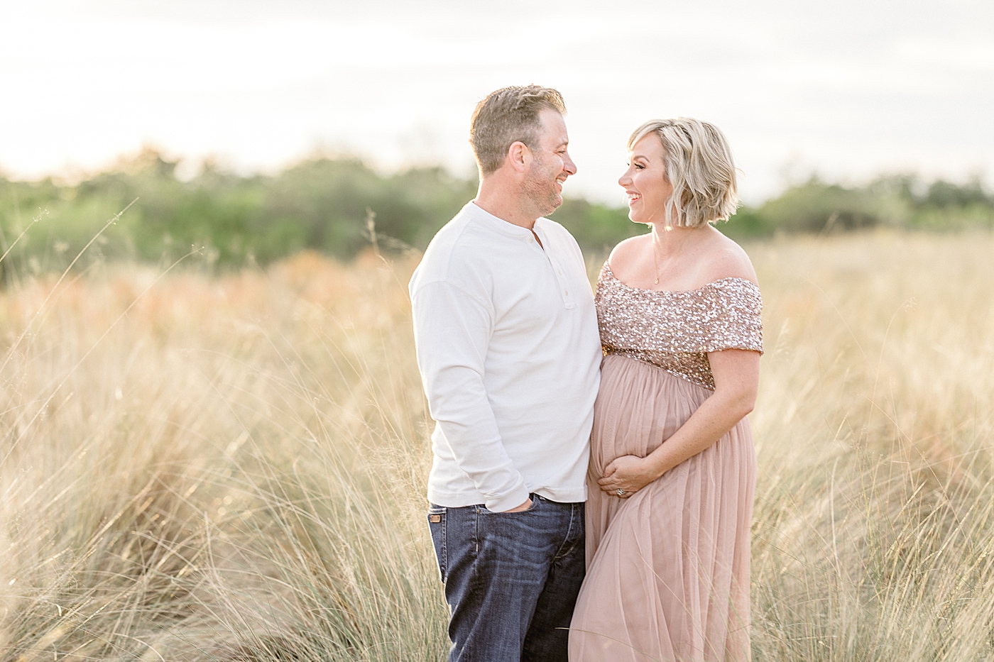 Photo of Mom in a blush sequin maternity gown looking at her husband. Photo by Brittany Elise Photography.
