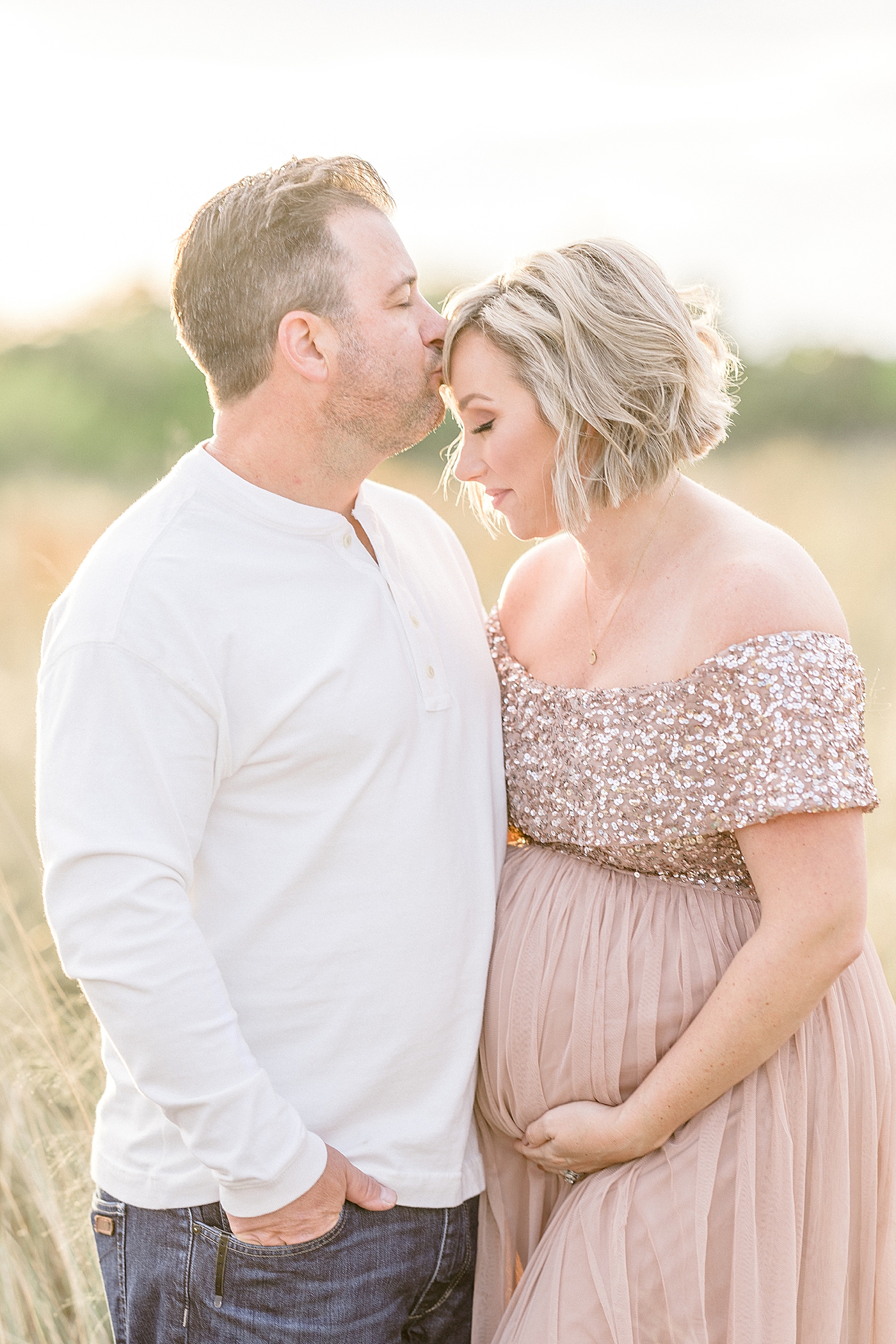 Husband kissing his wife on forehead during maternity session at Cypress Point Park with Brittany Elise Photography.