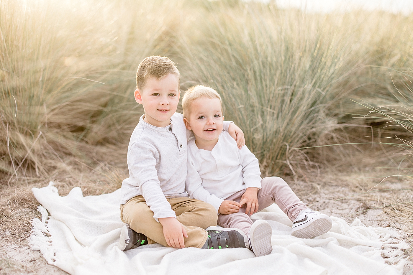 Two brothers sitting on a blanket with sunset behind them. Photo by Brittany Elise Photography.