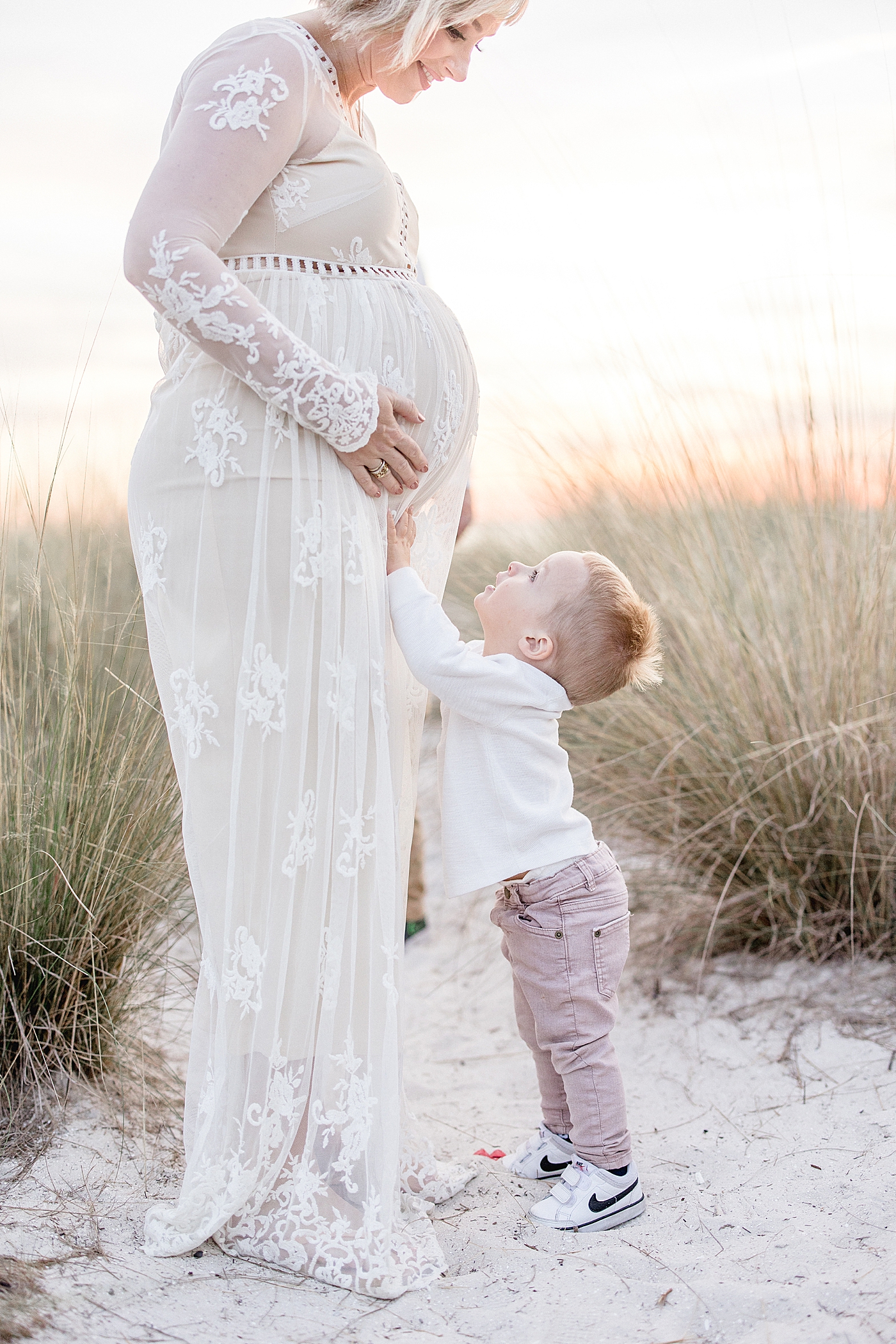 Toddler son looking up at Mom and touching her pregnant belly. Photo by Brittany Elise Photography.