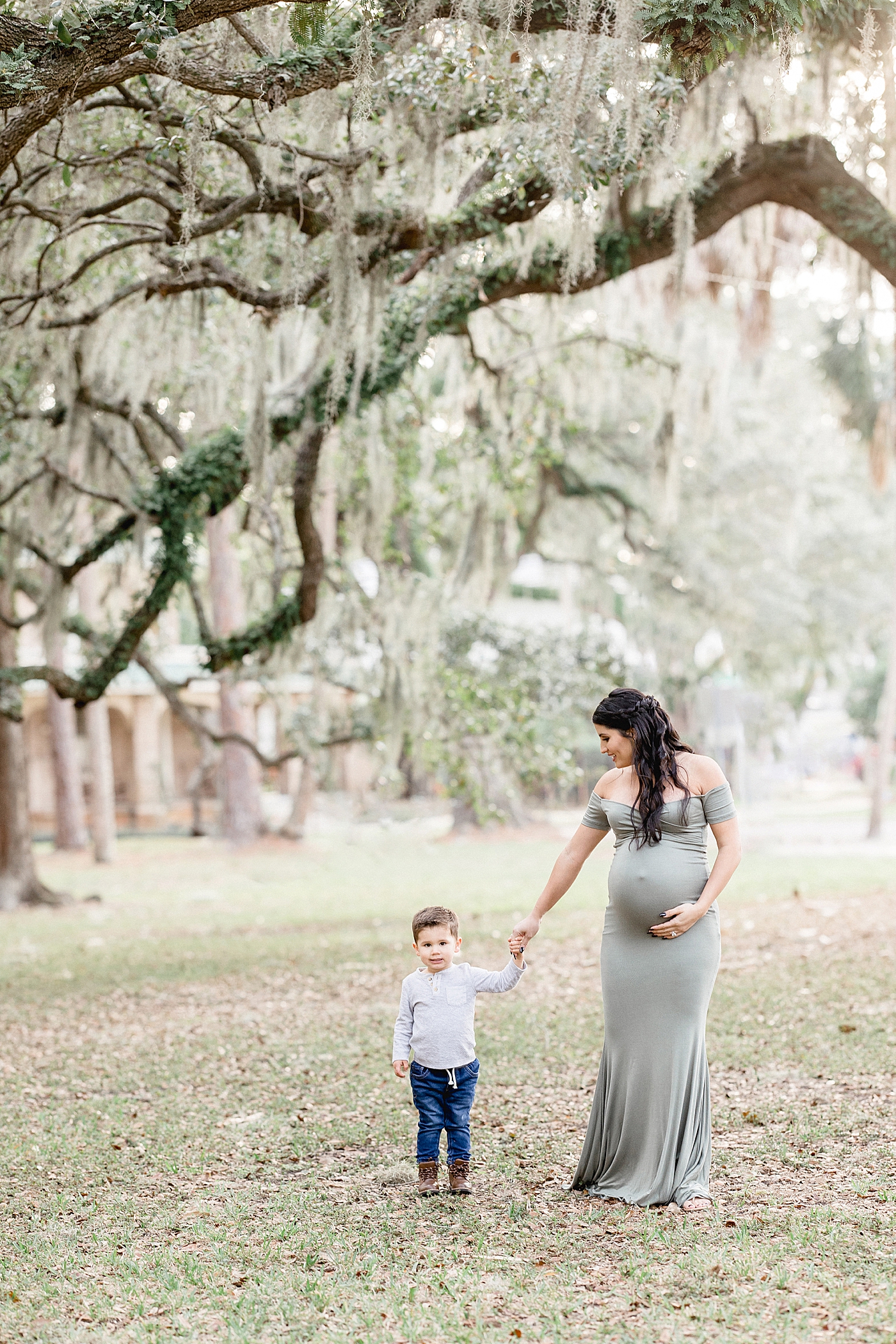 Mom and son walking together under the oaks during maternity session with Brittany Elise Photography.