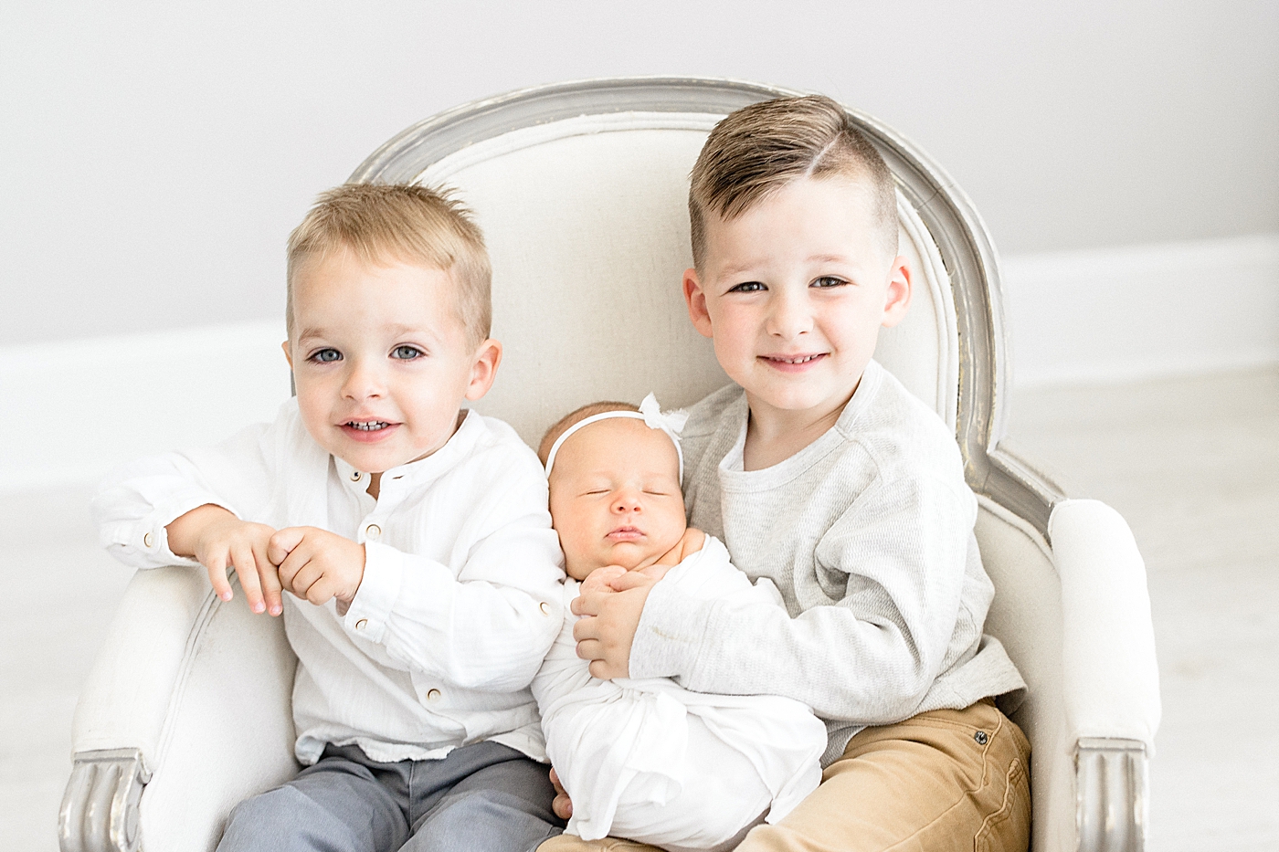 Sibling photo in chair during baby girl's newborn session in the studio. Photo by Brittany Elise Photography.
