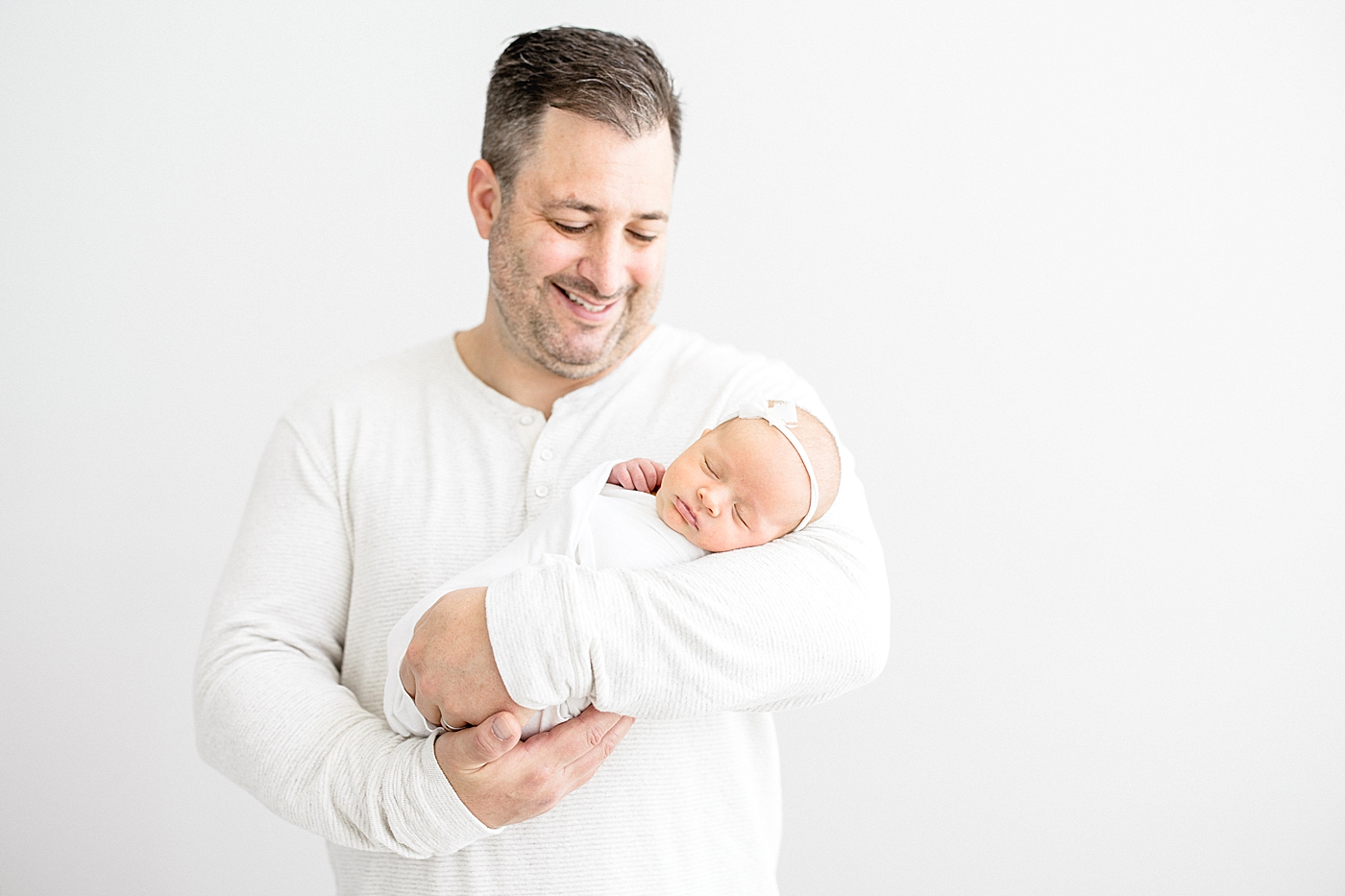 Dad looking down at his daughter for baby girl's newborn session in the studio. Photo by Brittany Elise Photography.