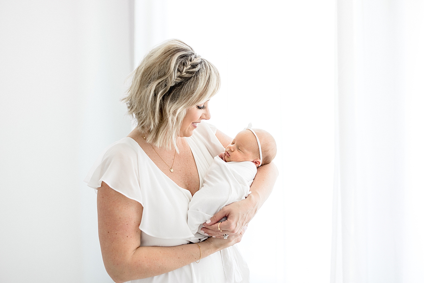 Mom looking at her daughter during baby girl's newborn session in the studio. Photo by Brittany Elise Photography.