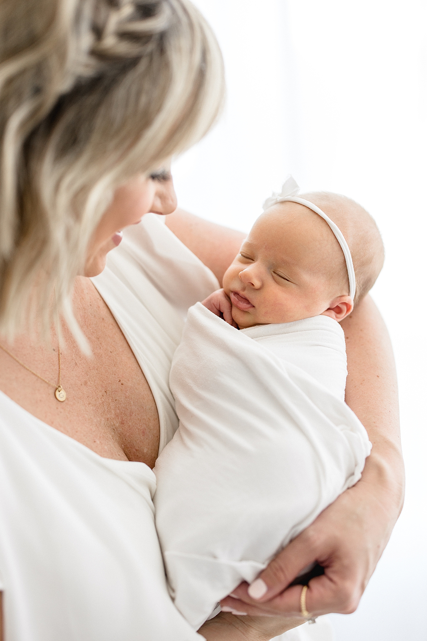 Mom looking down at her daughter during baby girl's studio newborn session. Photo by Brittany Elise Photography.