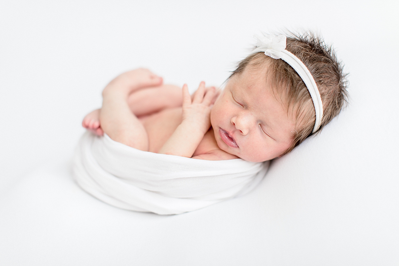 Baby girl swaddled in all white for newborn photos with Brittany Elise Photography.
