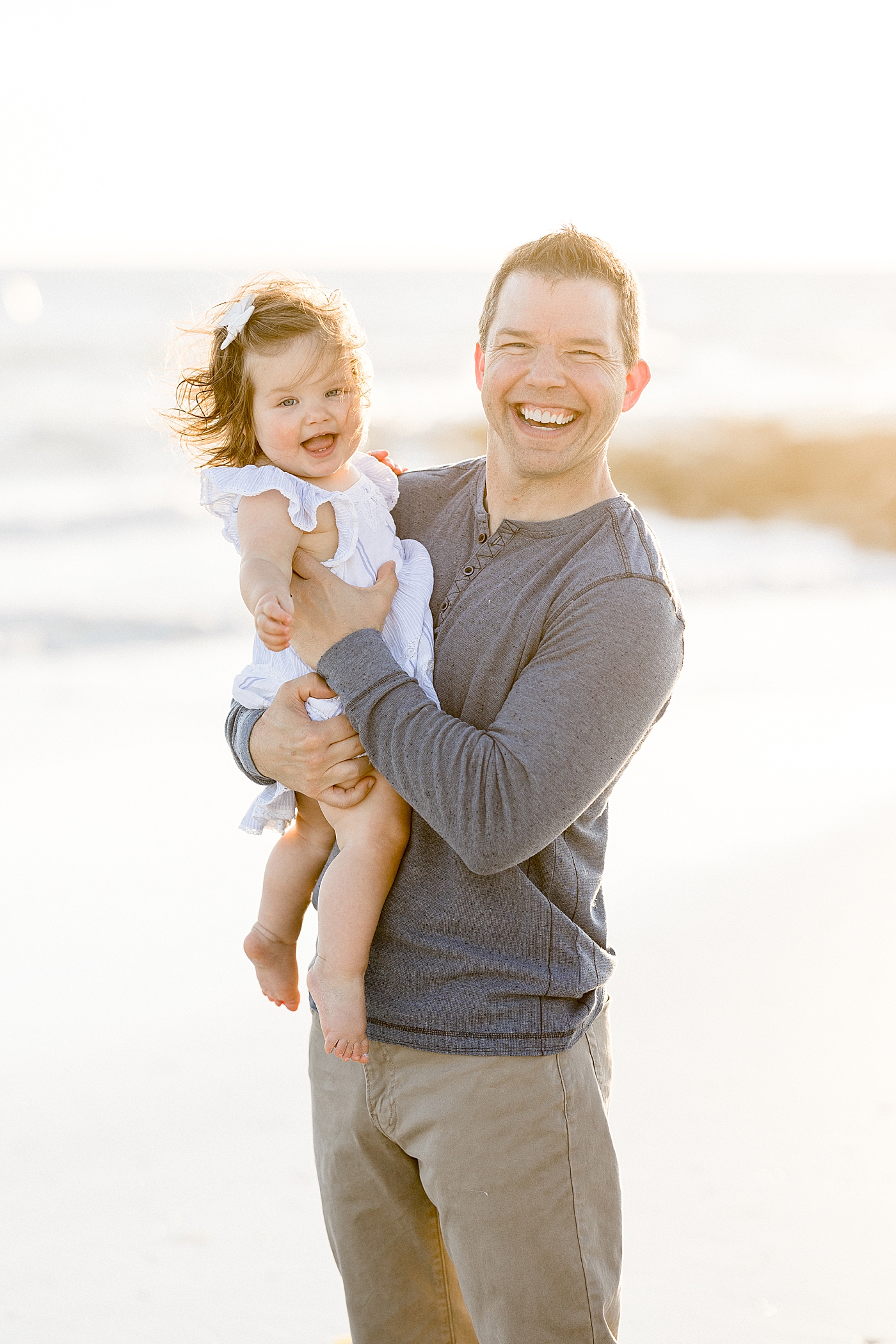 Dad holding his daughter at sunset on the beach. Photo by Brittany Elise Photography.