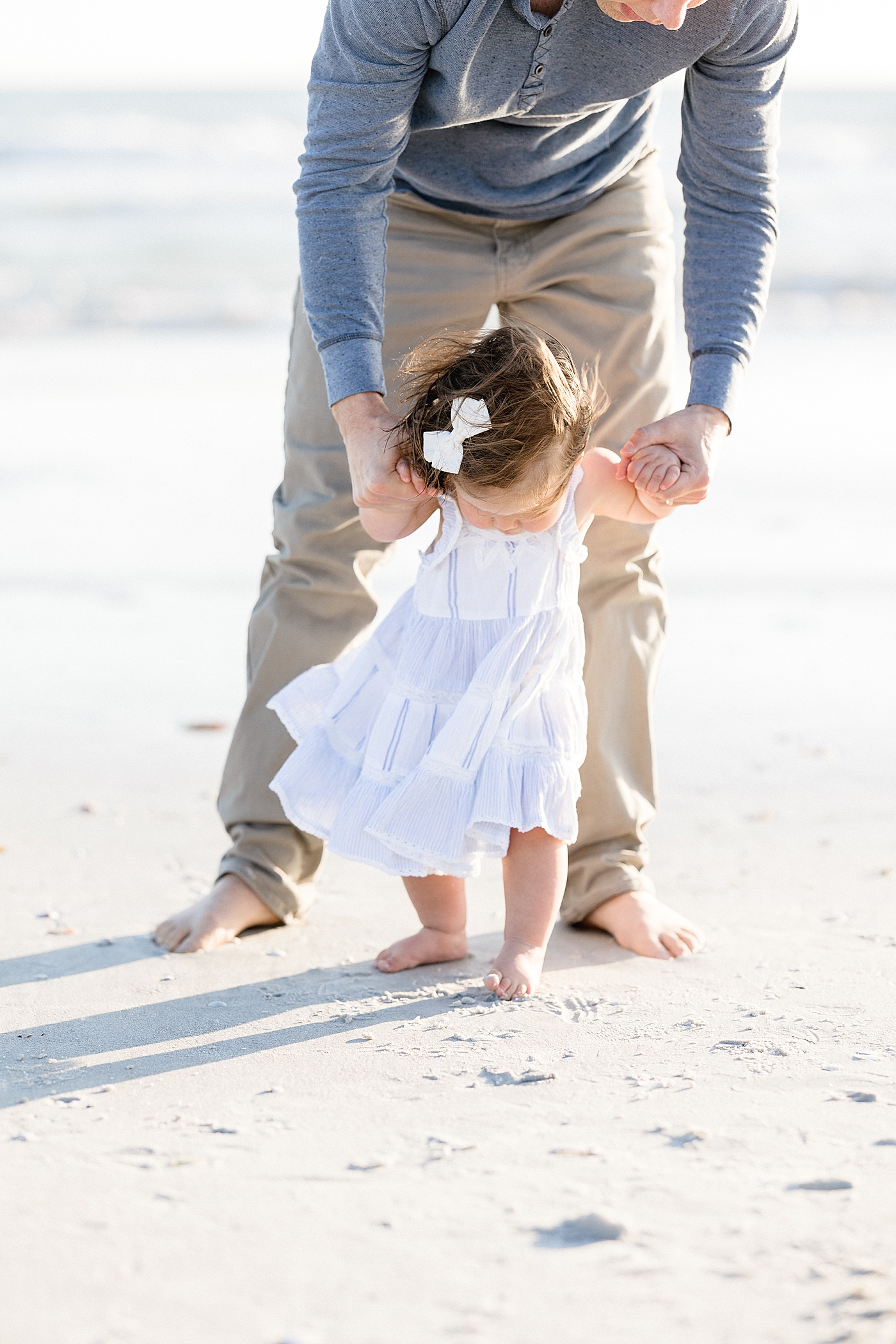 Dad walking with his baby girl on the beach. Photo by Brittany Elise Photography.