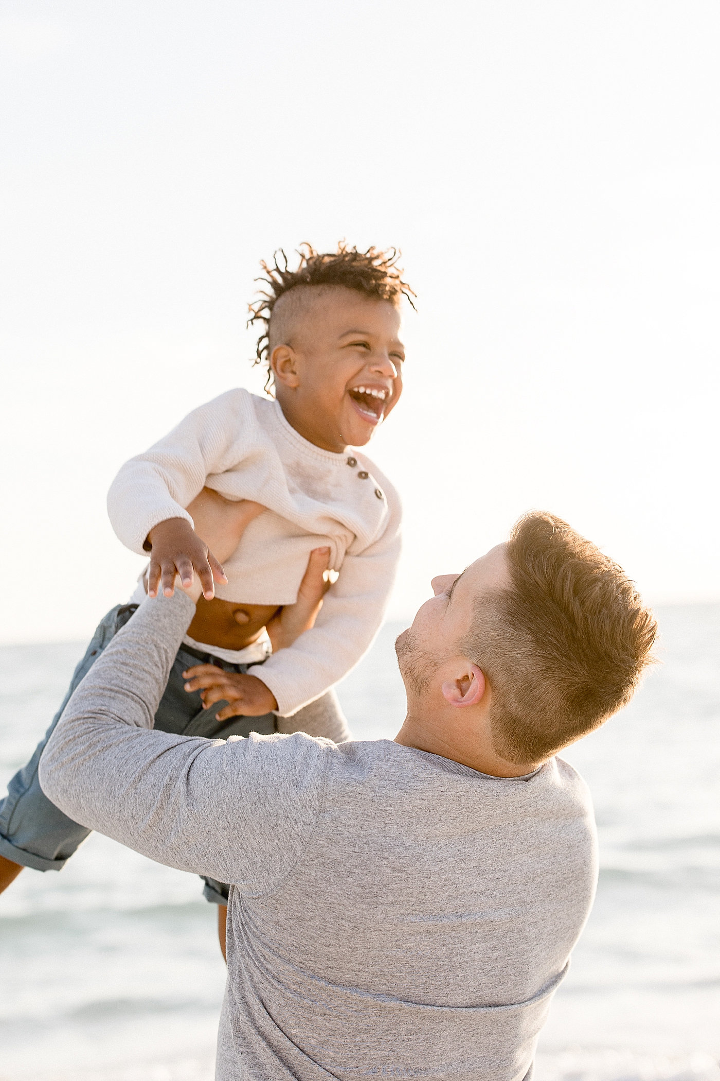 Dad holding son up in the air and he's laughing. Photo by Brittany Elise Photography.