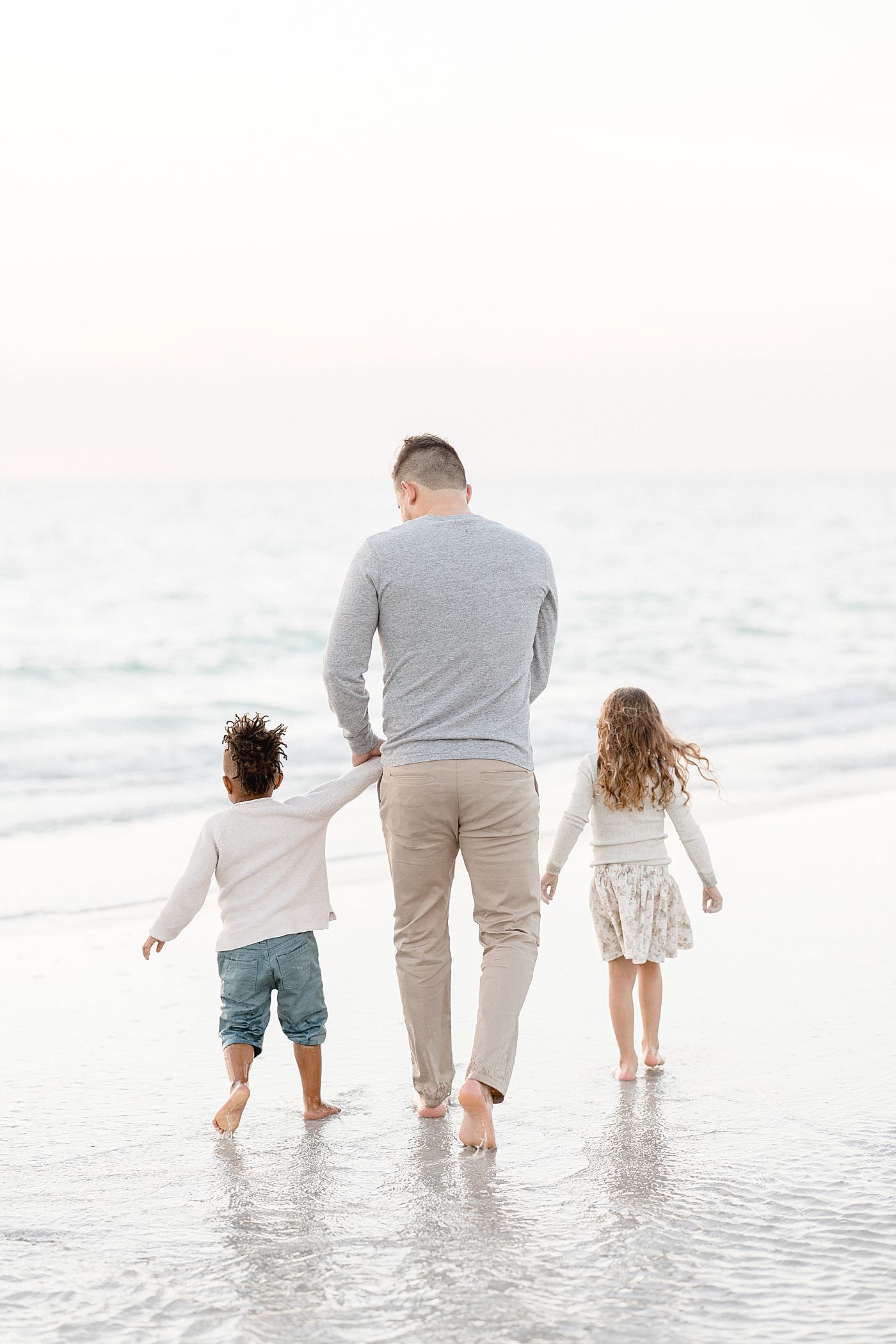 Dad walking down the beach with his son and daughter. Photo by Brittany Elise Photography.