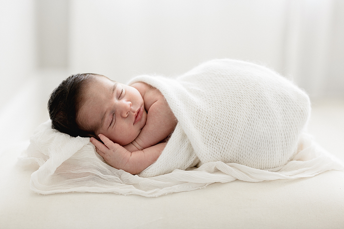 Baby boy swaddled and sleeping during newborn photos. Photo by Brittany Elise Photography.