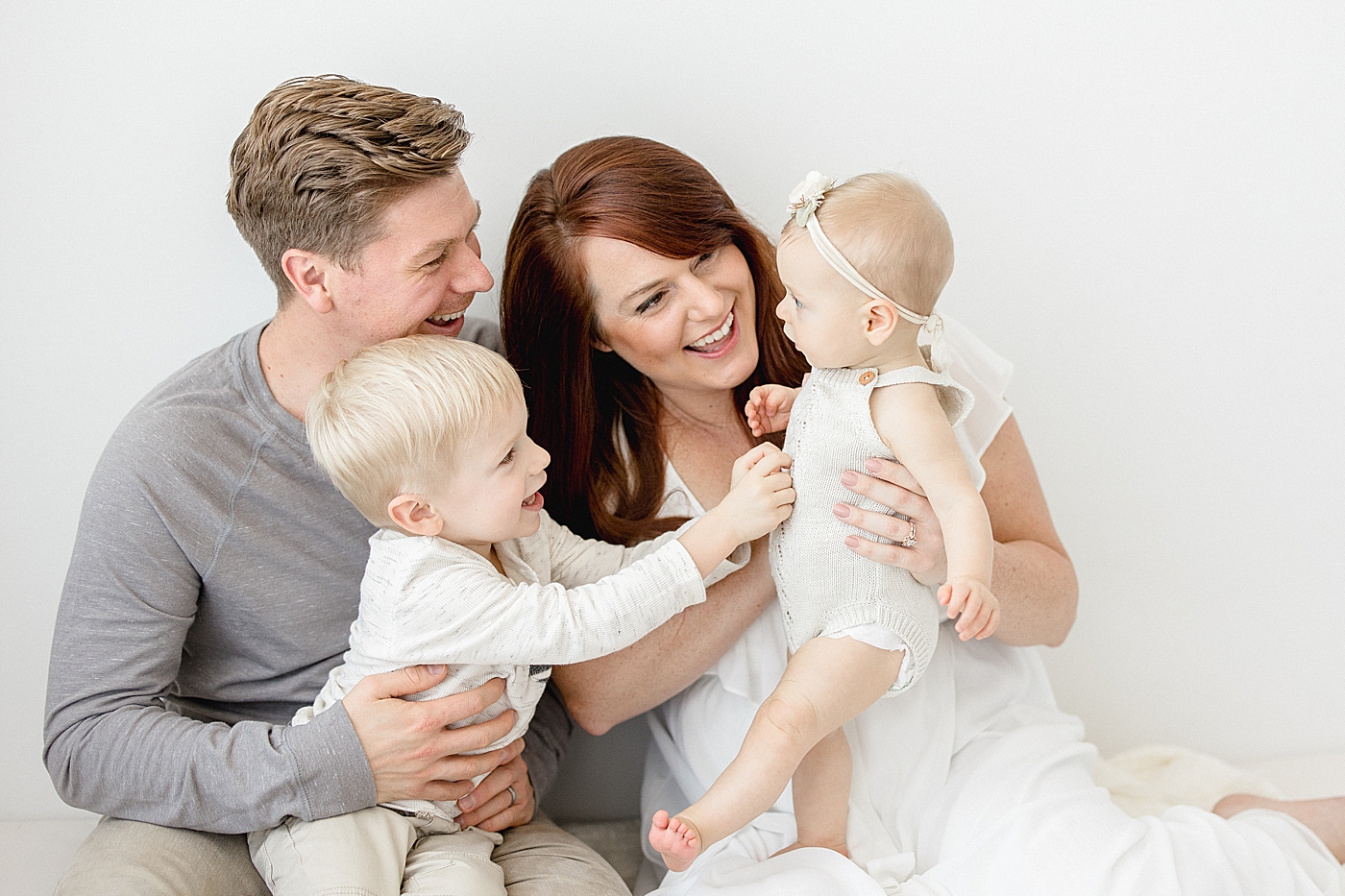 Family interacting during baby sisters six month milestone session in studio with Brittany Elise Photography.