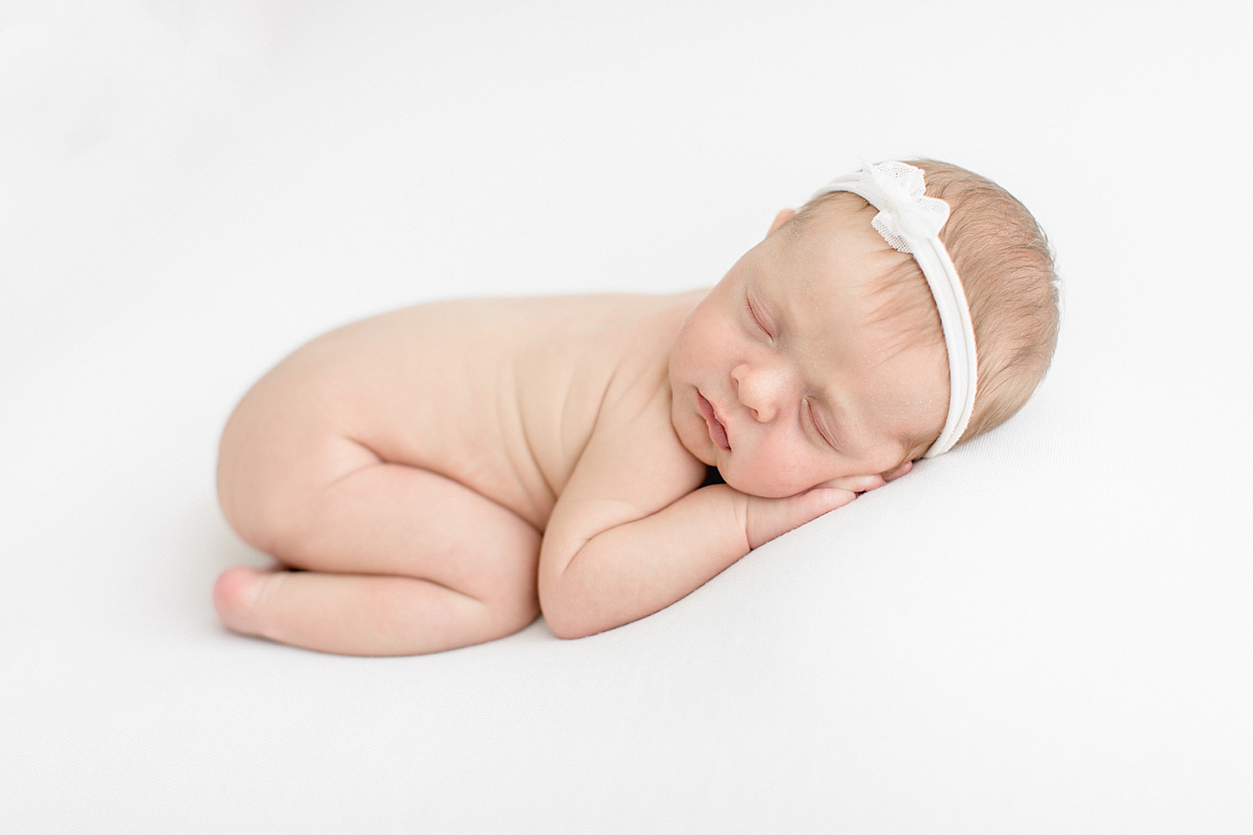Baby girl curled up on her stomach for newborn photos. Photo by Brittany Elise Photography.
