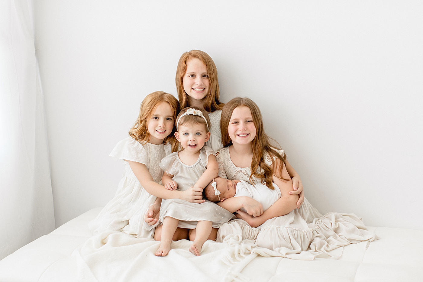 Four big sisters holding their baby sister at newborn session in Tampa. Photo by Brittany Elise Photography.