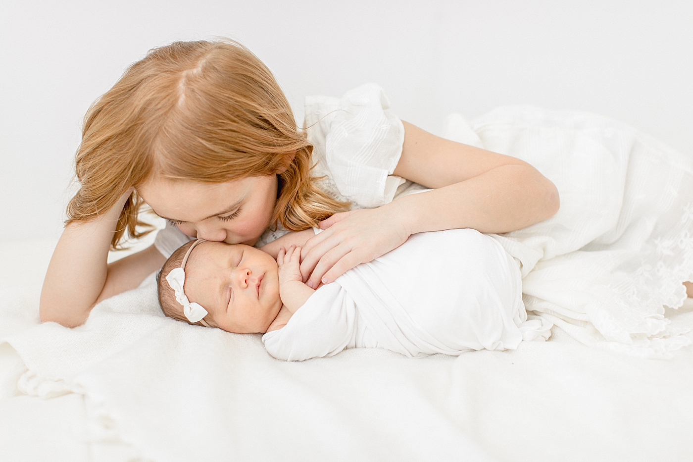 Big sister giving baby sister a kiss. Photo by Brittany Elise Photography.