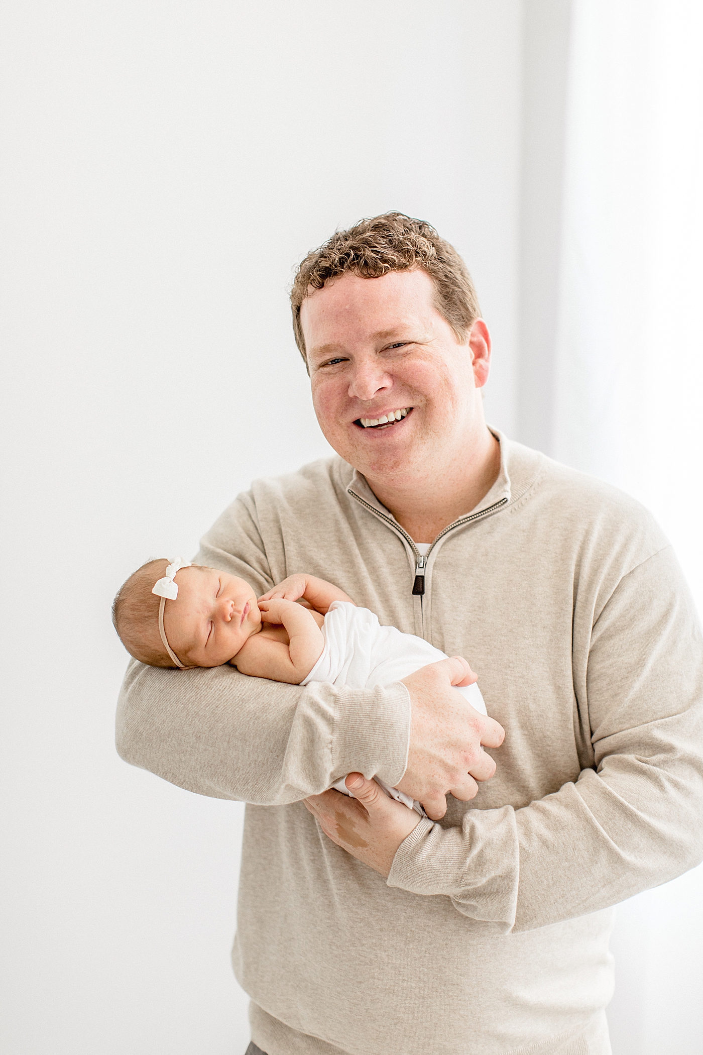 Dad smiling while holding his fifth daughter for her newborn photoshoot with Brittany Elise Photography.