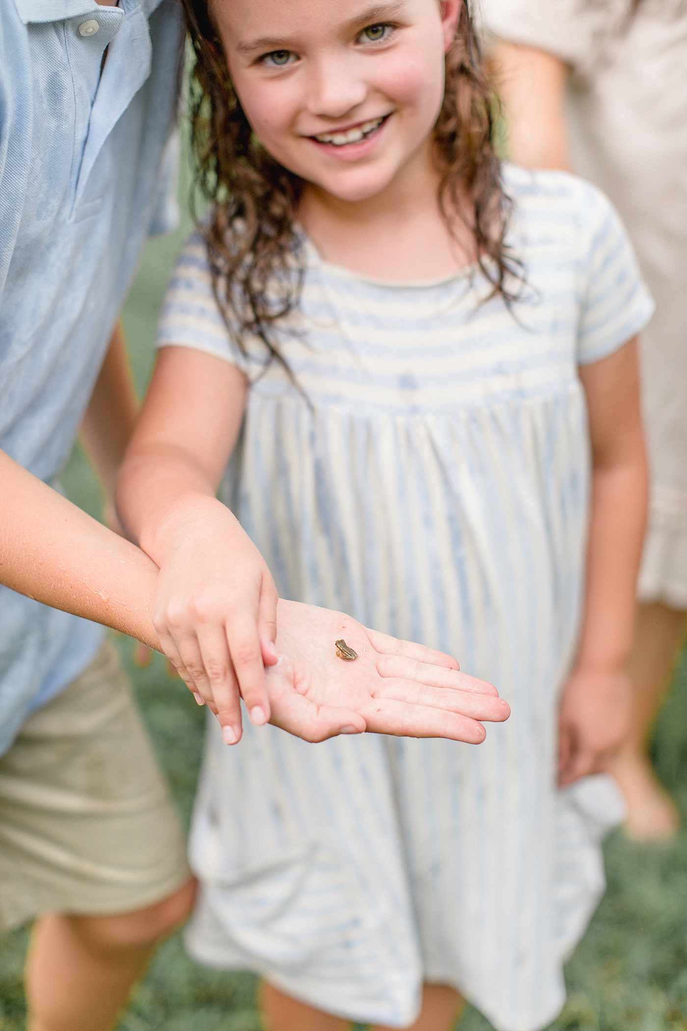 Family photoshoot in the rain. Daughter catches a small frog. Photo by Brittany Elise Photography.