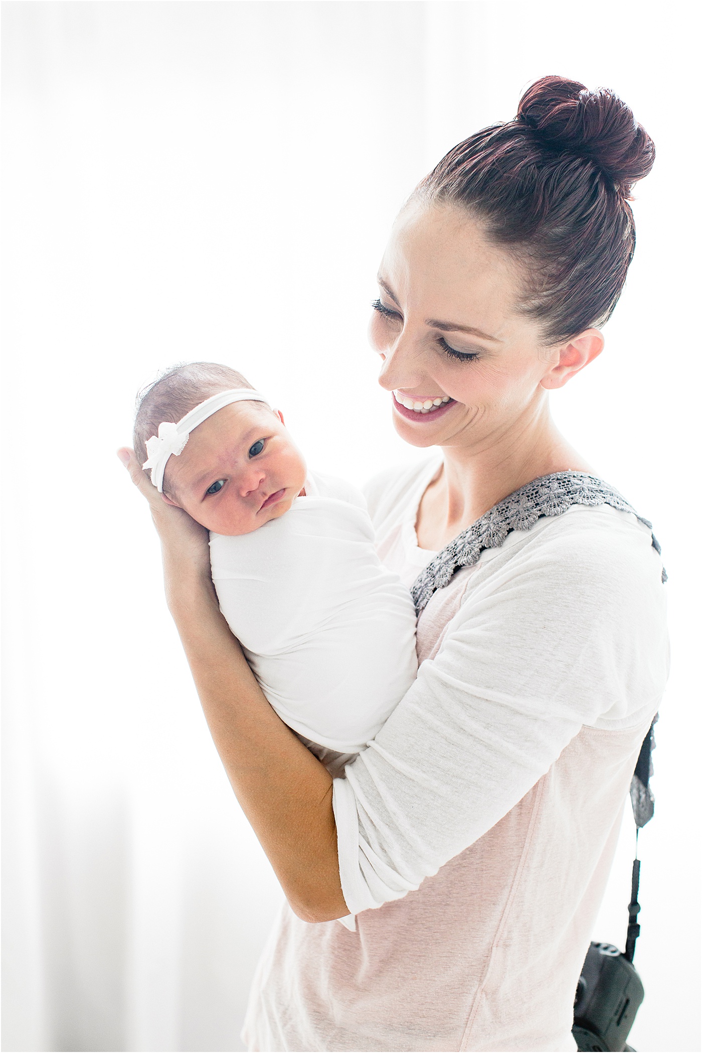 Backlit image of Brittany Elise Photography holding swaddled newborn during studio session in Tampa.
