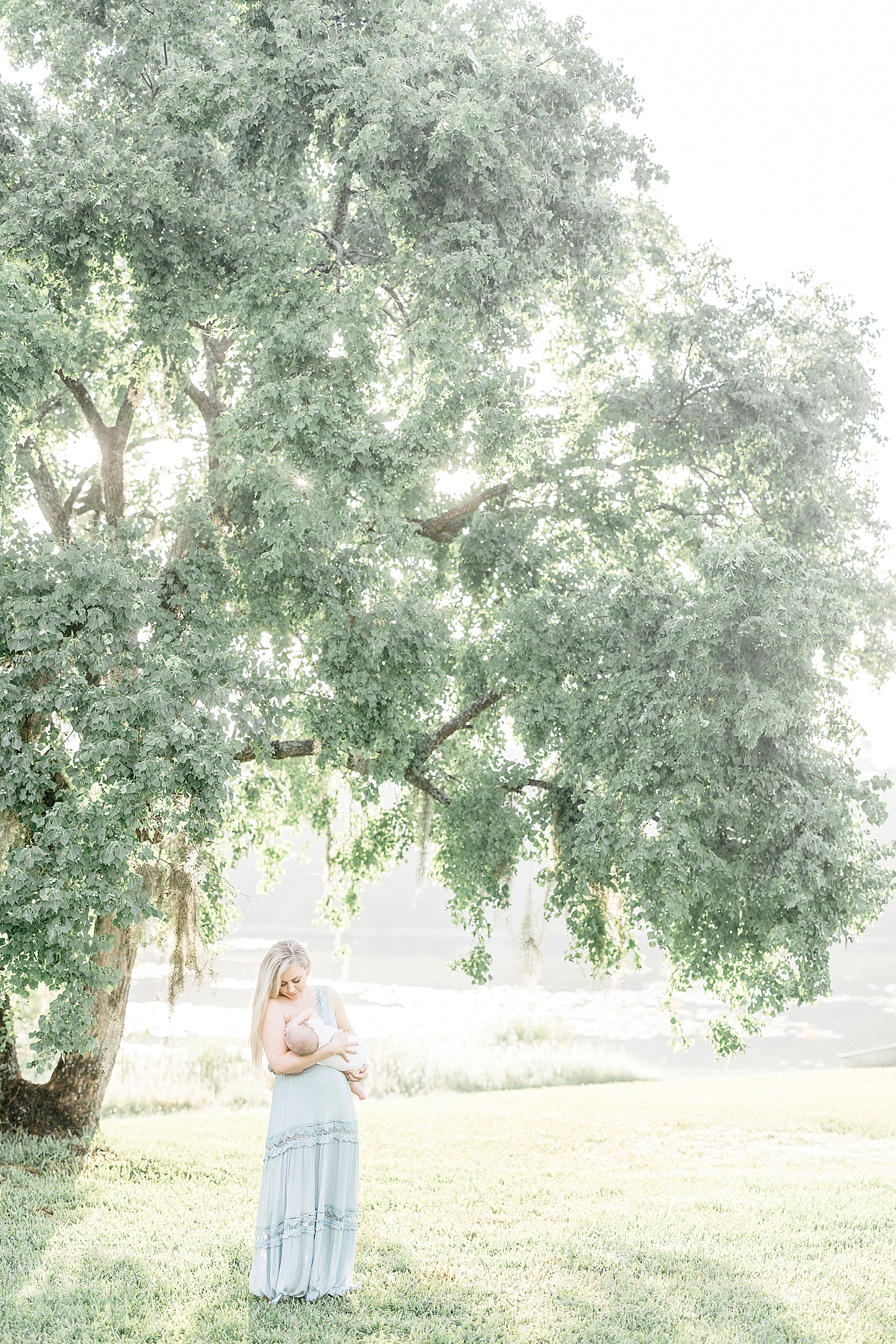 Mom nursing baby outside under beautiful tree during family photoshoot with Brittany Elise Photography.