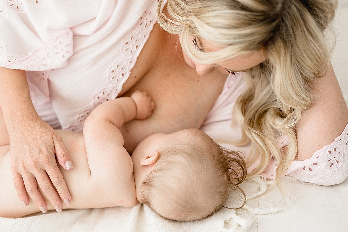 Mom laying down breastfeeding her baby. Photo by Brittany Elise Photography.