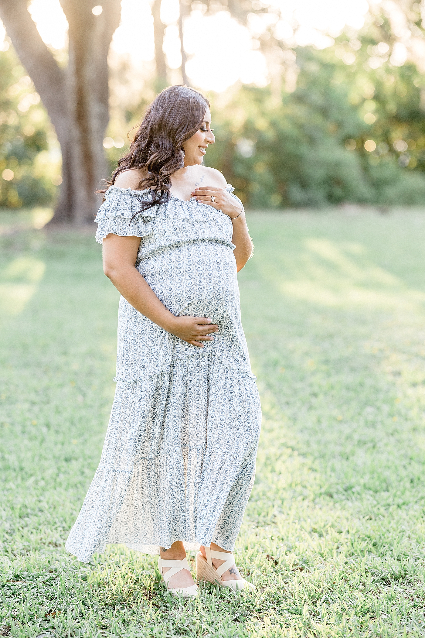 Mom standing in field holding her pregnant belly. Photo by Brittany Elise Photography.
