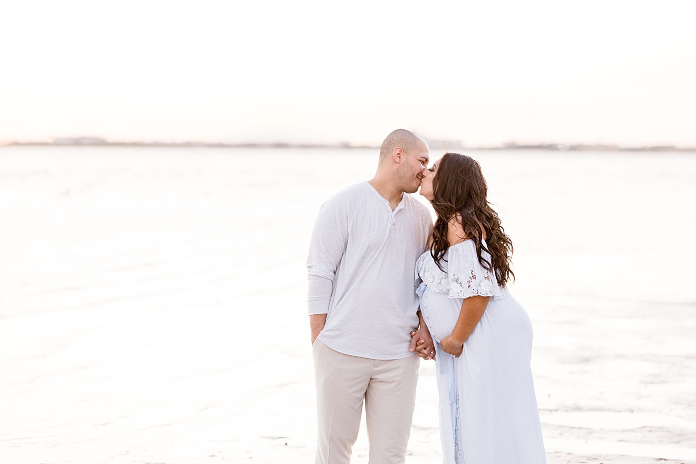 Couple kissing during maternity photoshoot at the beach in Tampa, FL. Photo by Brittany Elise Photography.