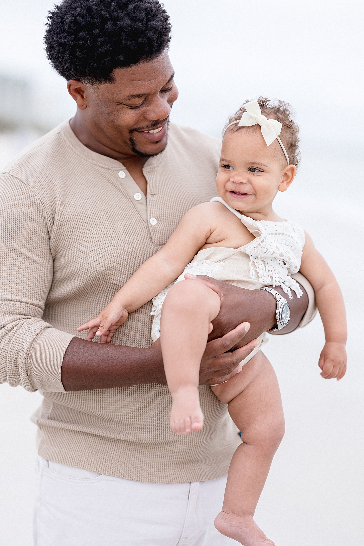 Dad holding his baby girl for her first birthday session on the beach. Photo by Brittany Elise Photography.