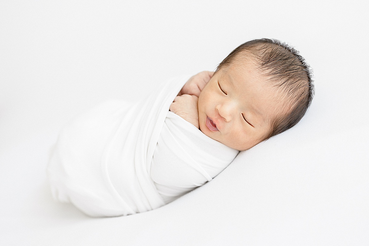 Newborn baby boy swaddled in white. Photo by Brittany Elise Photography.