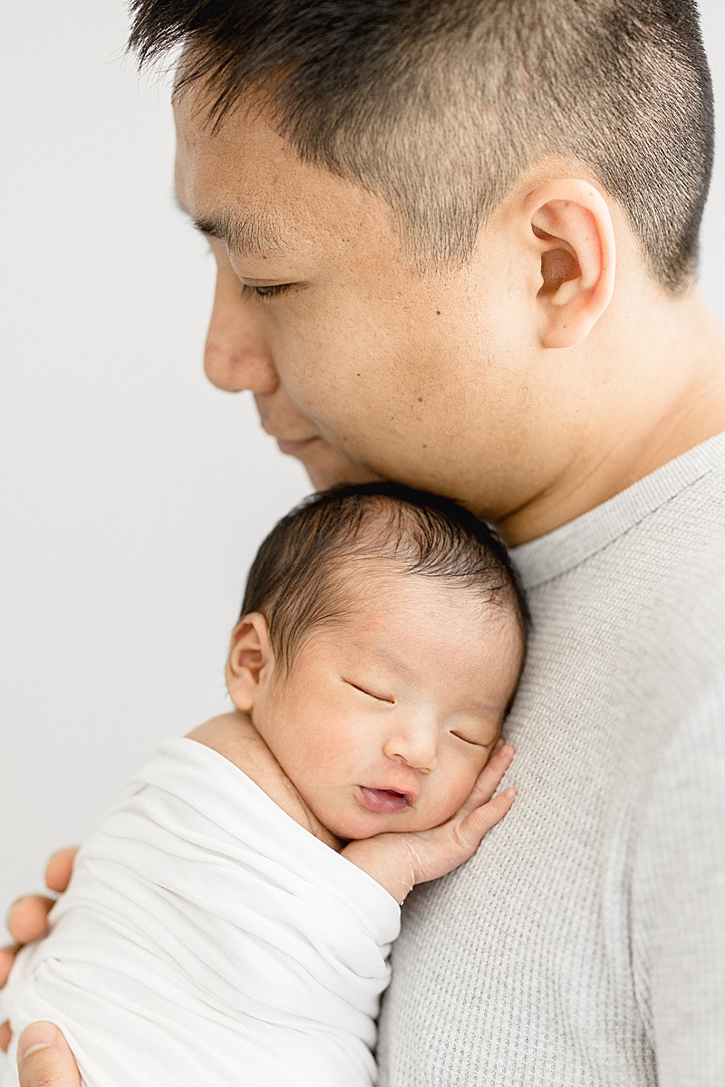 Dad holding his son for newborn photos. Photo by Brittany Elise Photography.