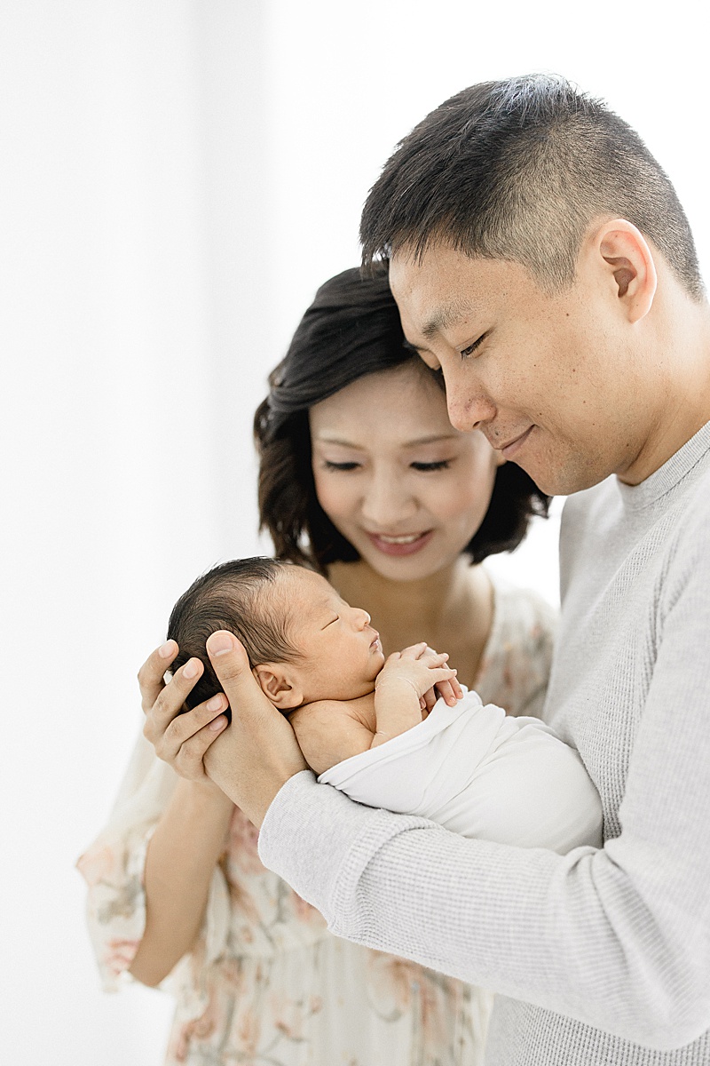 First-time parents hold their son for newborn photos. Photo by Brittany Elise Photography.