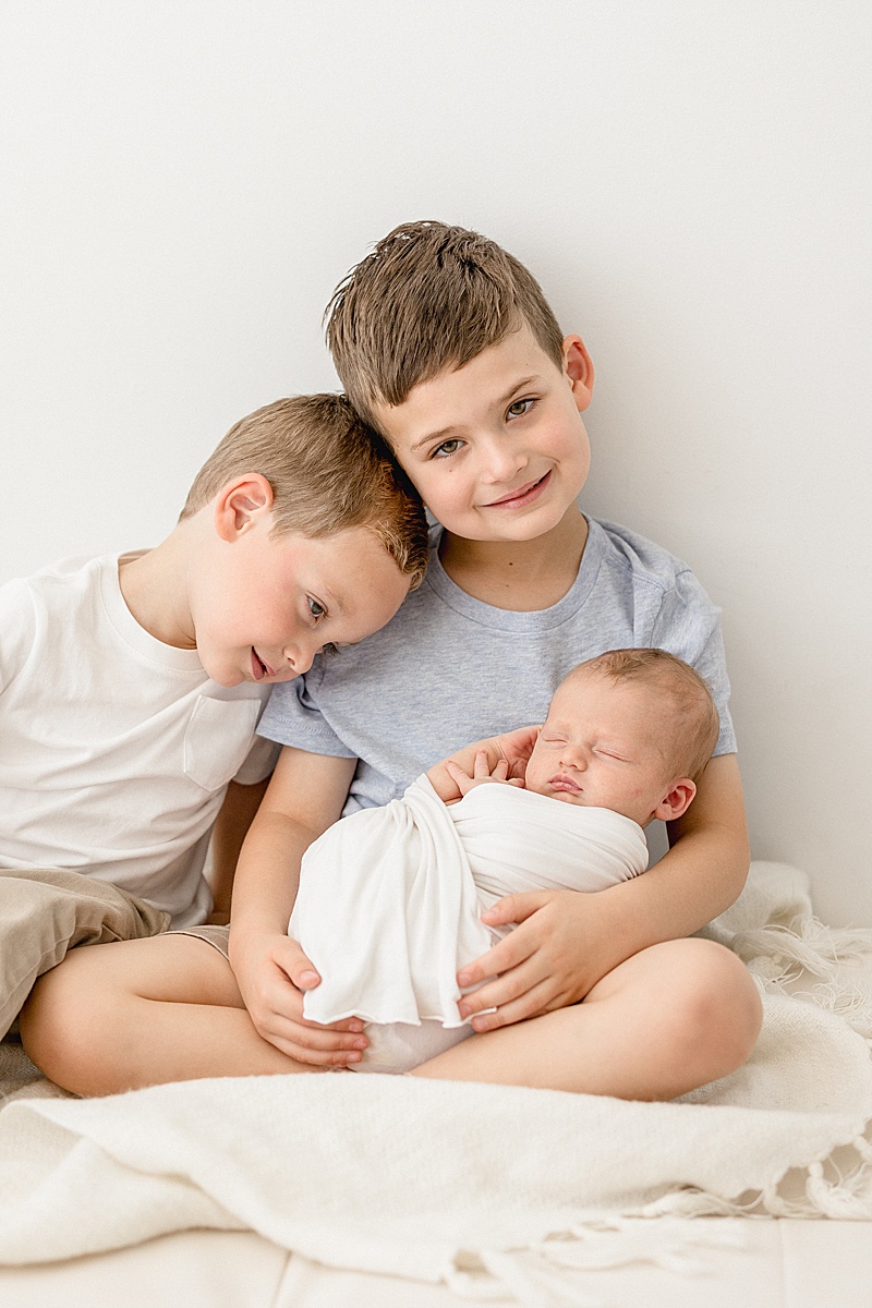 Three brothers together during baby brothers newborn session. Photo by Brittany Elise Photography.