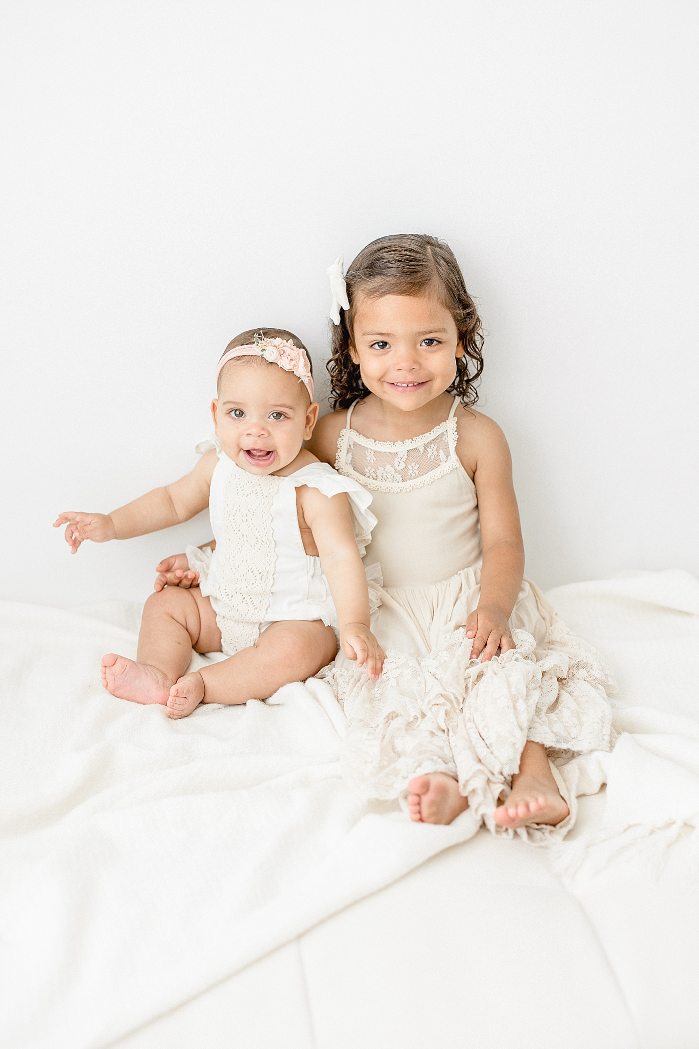 Two sisters sitting together for photos during milestone session. Photo by Brittany Elise Photography.