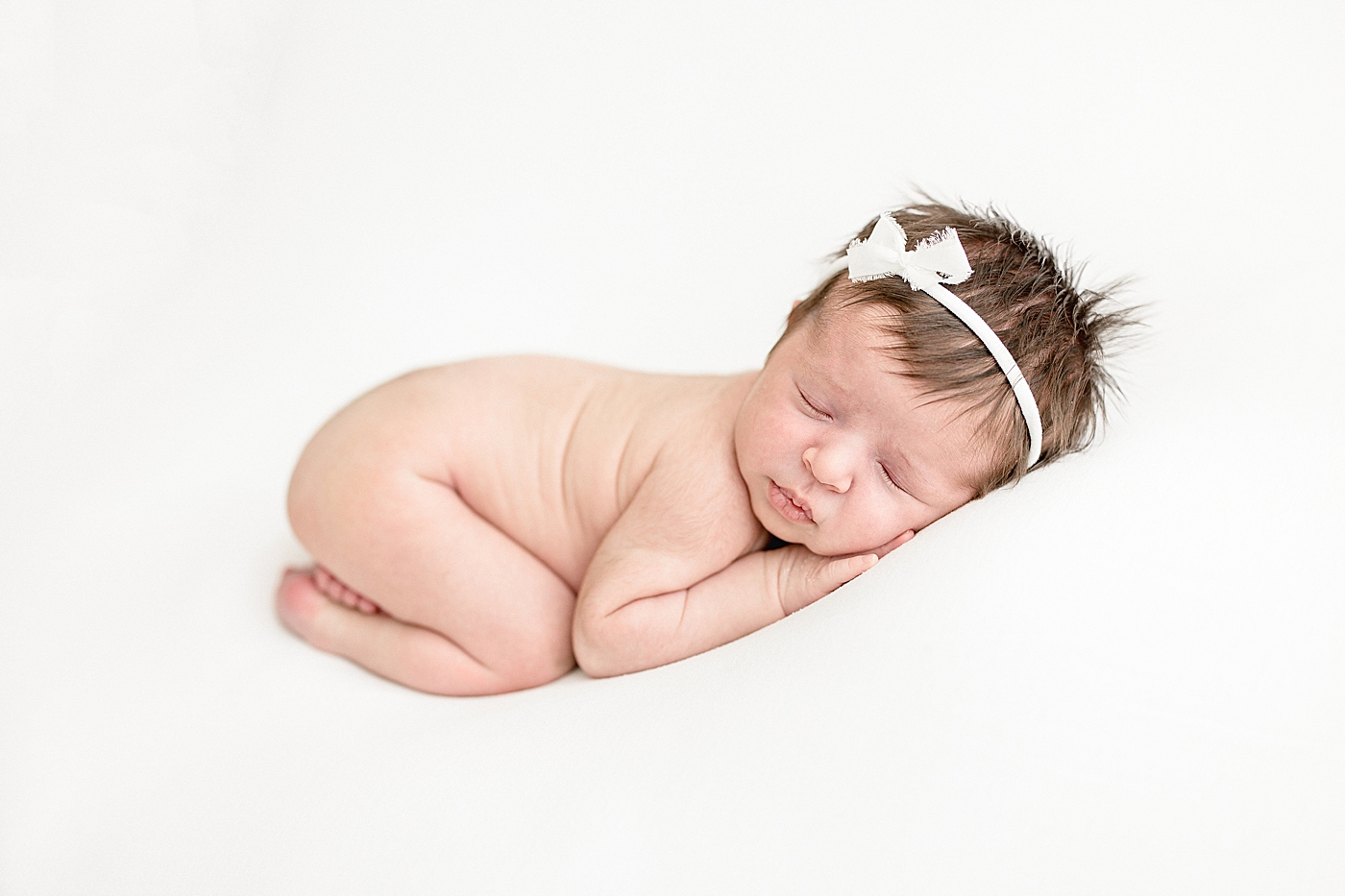 Baby girl curled up on her stomach for newborn photos. Photos by Brittany Elise Photography.