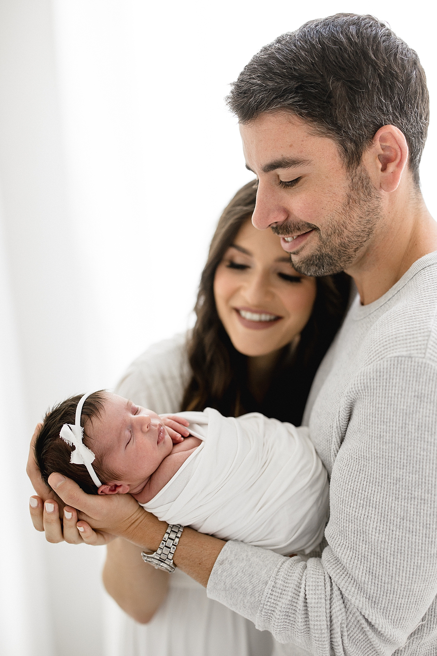 Mom and Dad holding and looking at their newborn baby girl. Photos by Brittany Elise Photography.