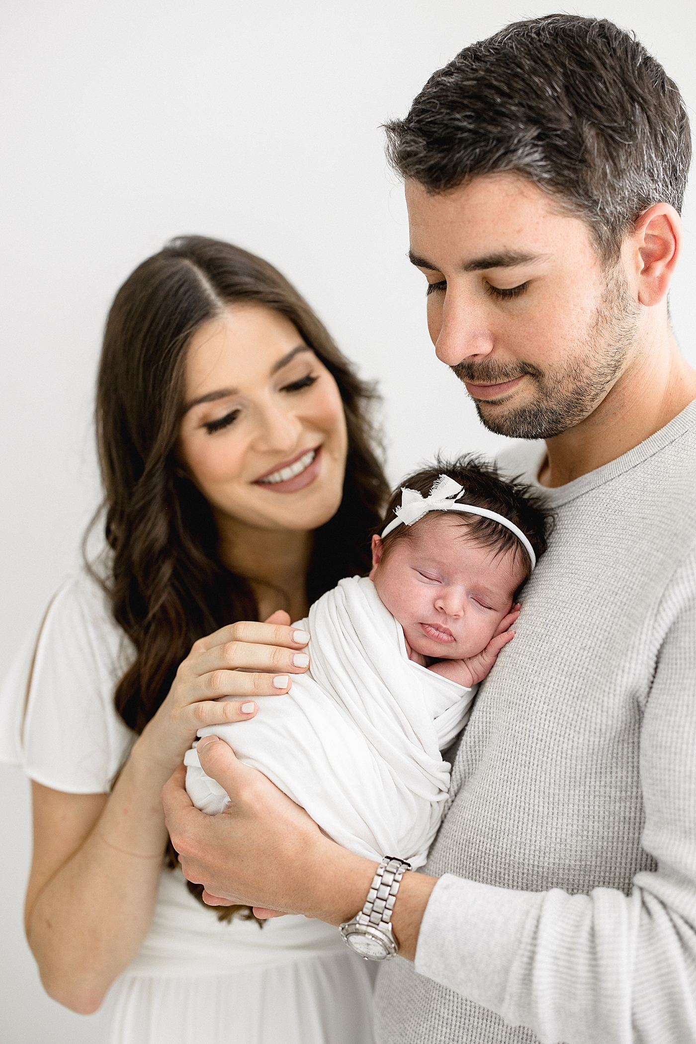 Mom and Dad holding and looking at their newborn baby girl. Photos by Brittany Elise Photography.