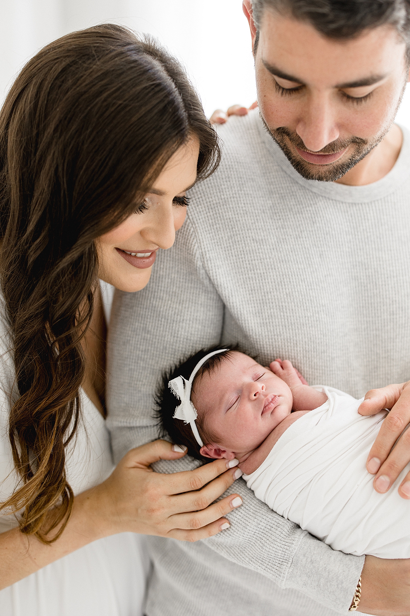 Dad is holding daughter and Mom is looking down at her. Photos by Brittany Elise Photography.