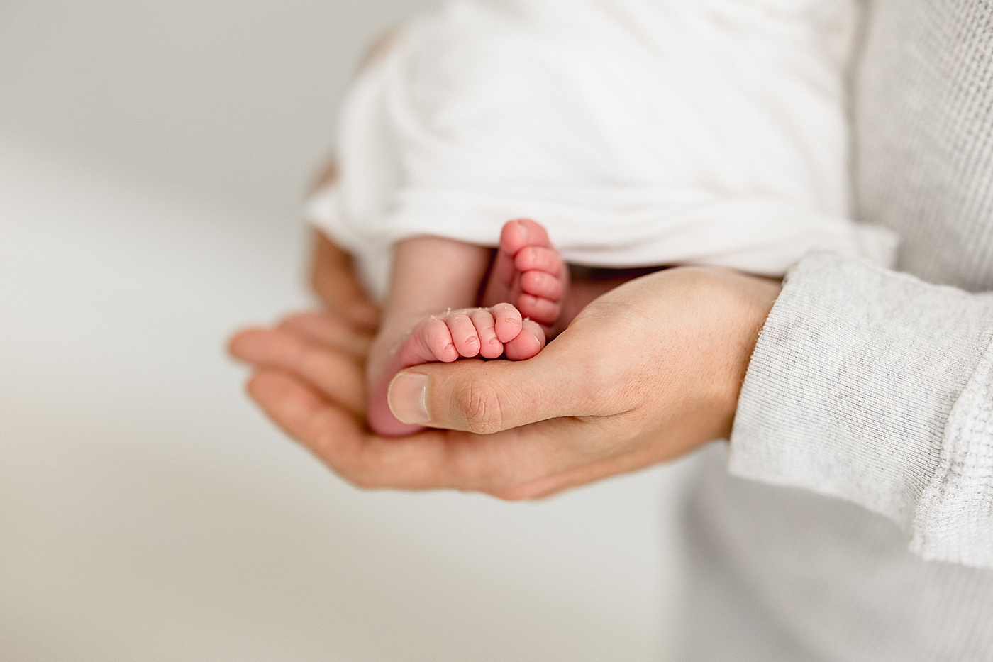 Newborn baby toes in Dad's hands. Photos by Brittany Elise Photography.