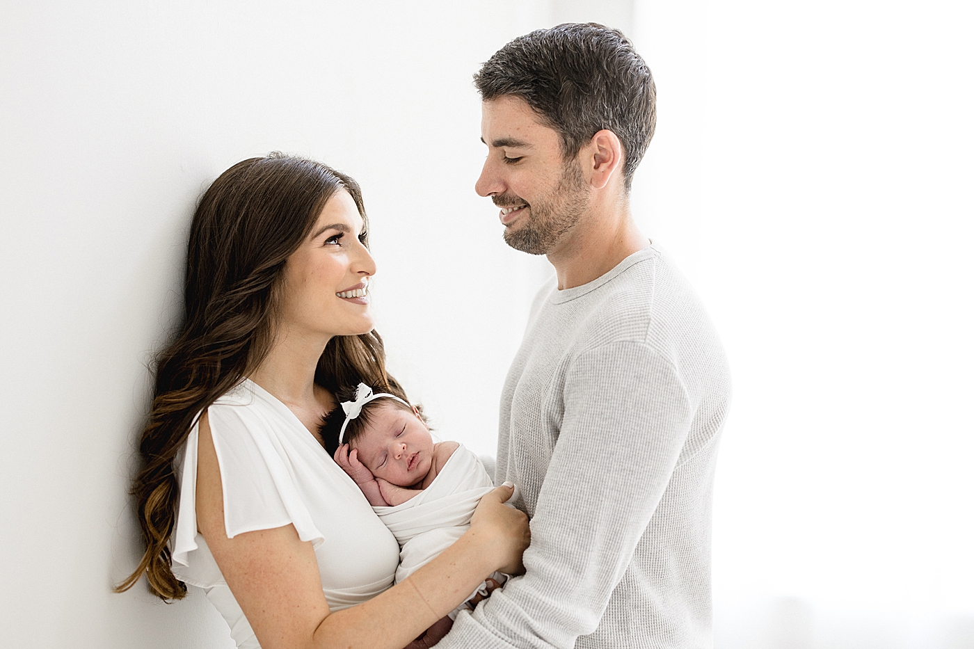 Parents looking at each other while holding their newborn daughter. Photos by Brittany Elise Photography.