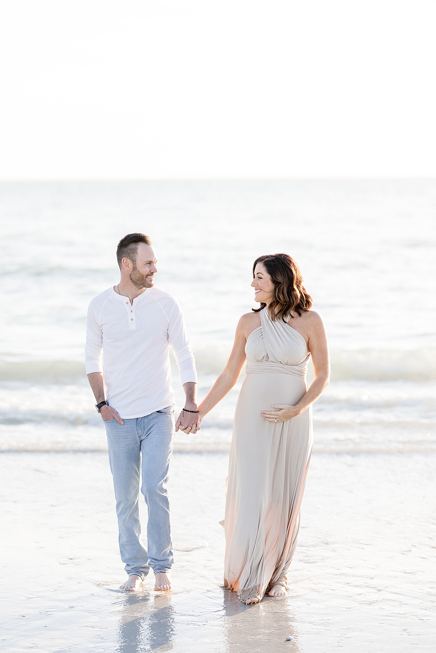 Expecting parents walking on the beach. Photo by Brittany Elise Photography.