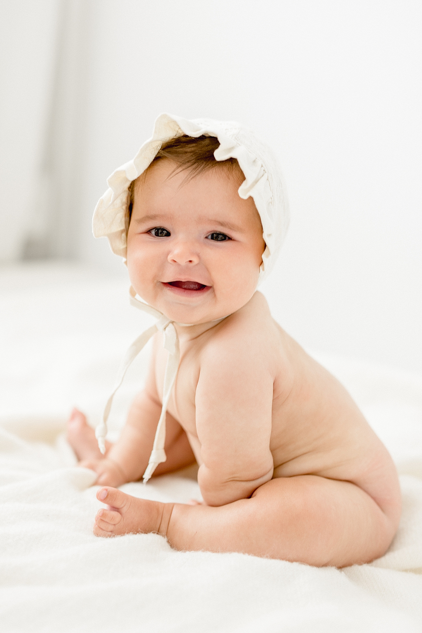 Six month old sitting and wearing a bonnet. Photos by Brittany Elise Photography.