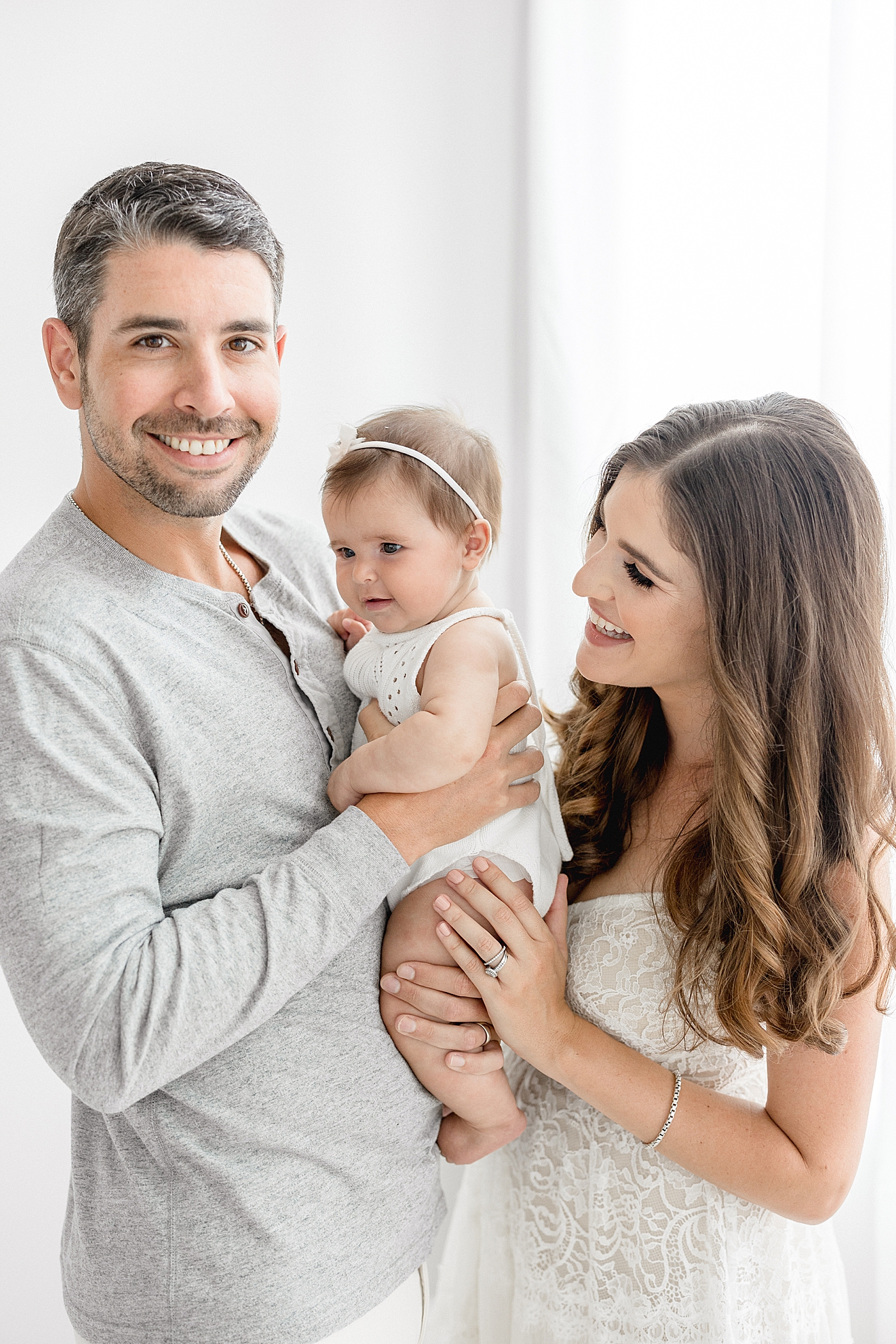 Parents hold six month old baby girl for photos. Photos by Brittany Elise Photography.