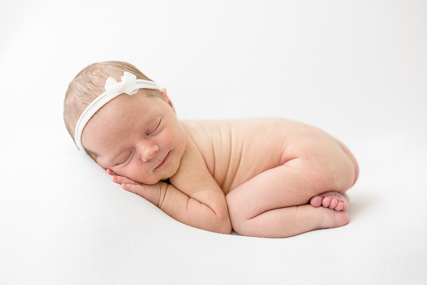 Newborn baby curled up on belly. Photo by Brittany Elise Photography.