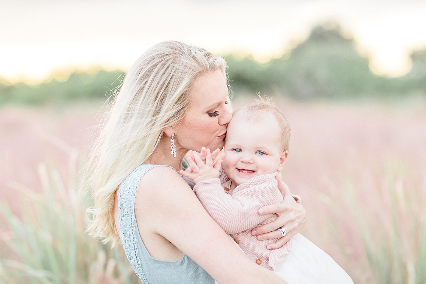 Mom kissing her one year old daughter and she's clapping. Photo by Brittany Elise Photography.