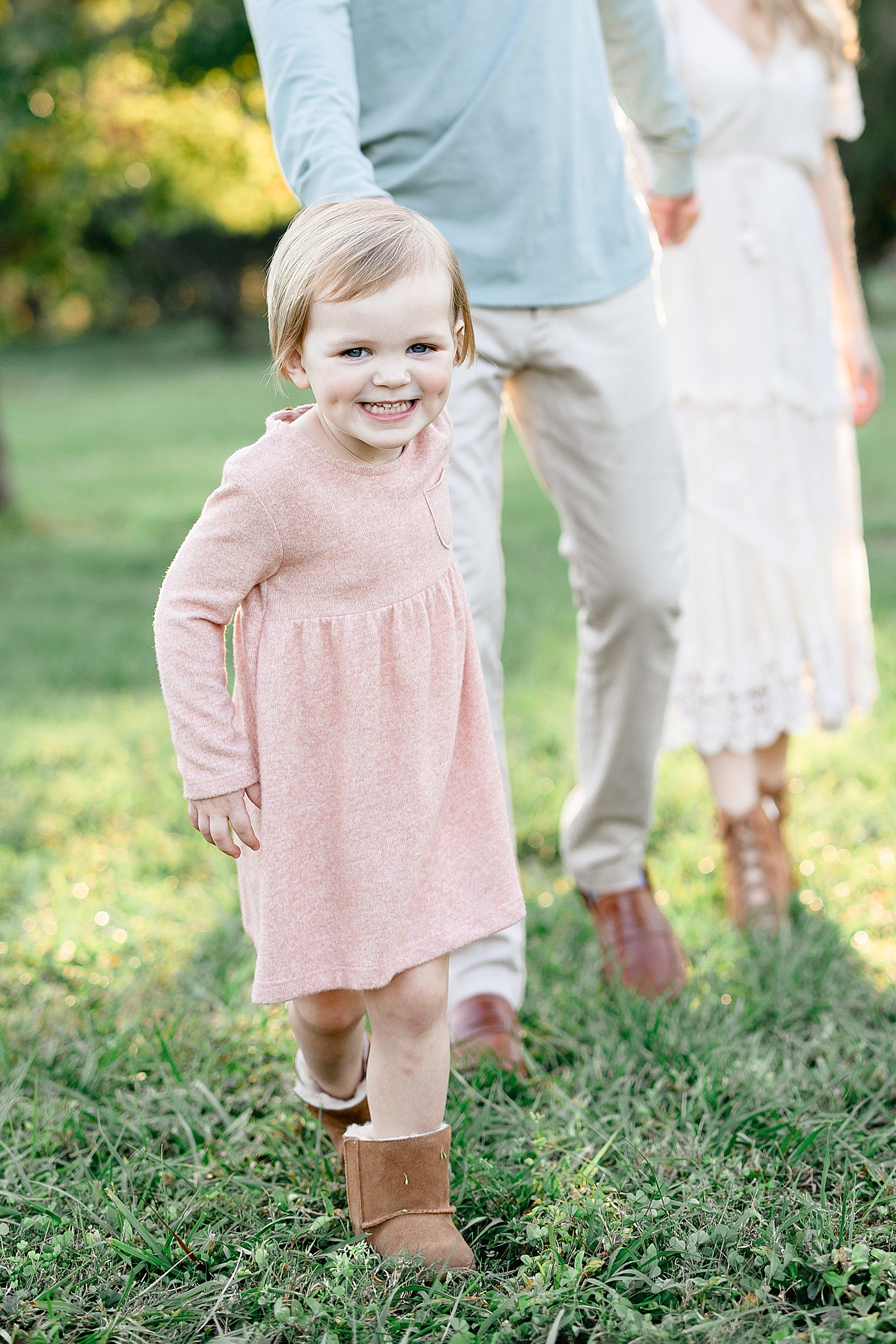 Toddler leading family as they walk through field for photos with Brittany Elise Photography.