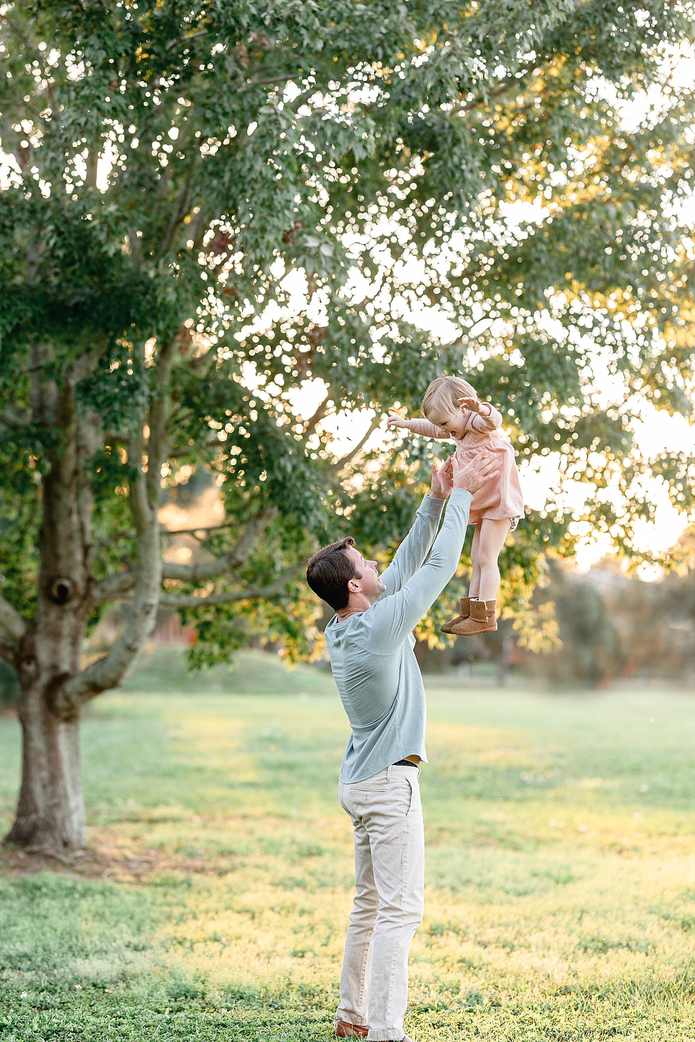 Dad throwing two year old daughter up in the air. Photo by Brittany Elise Photography.